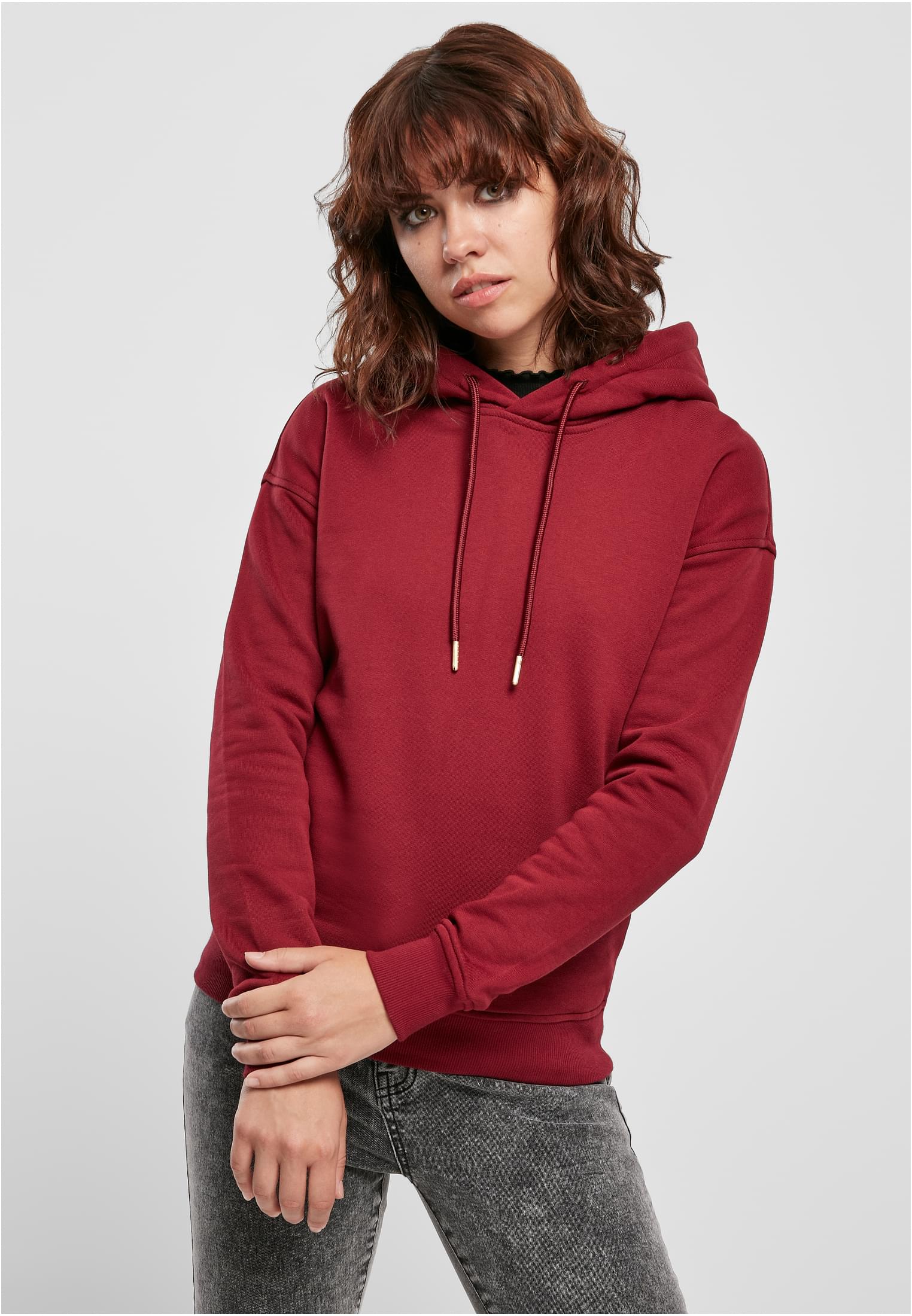 En kvinna som bär en terrakottafärgad Ladies Organic Hoody och mörka jeans.