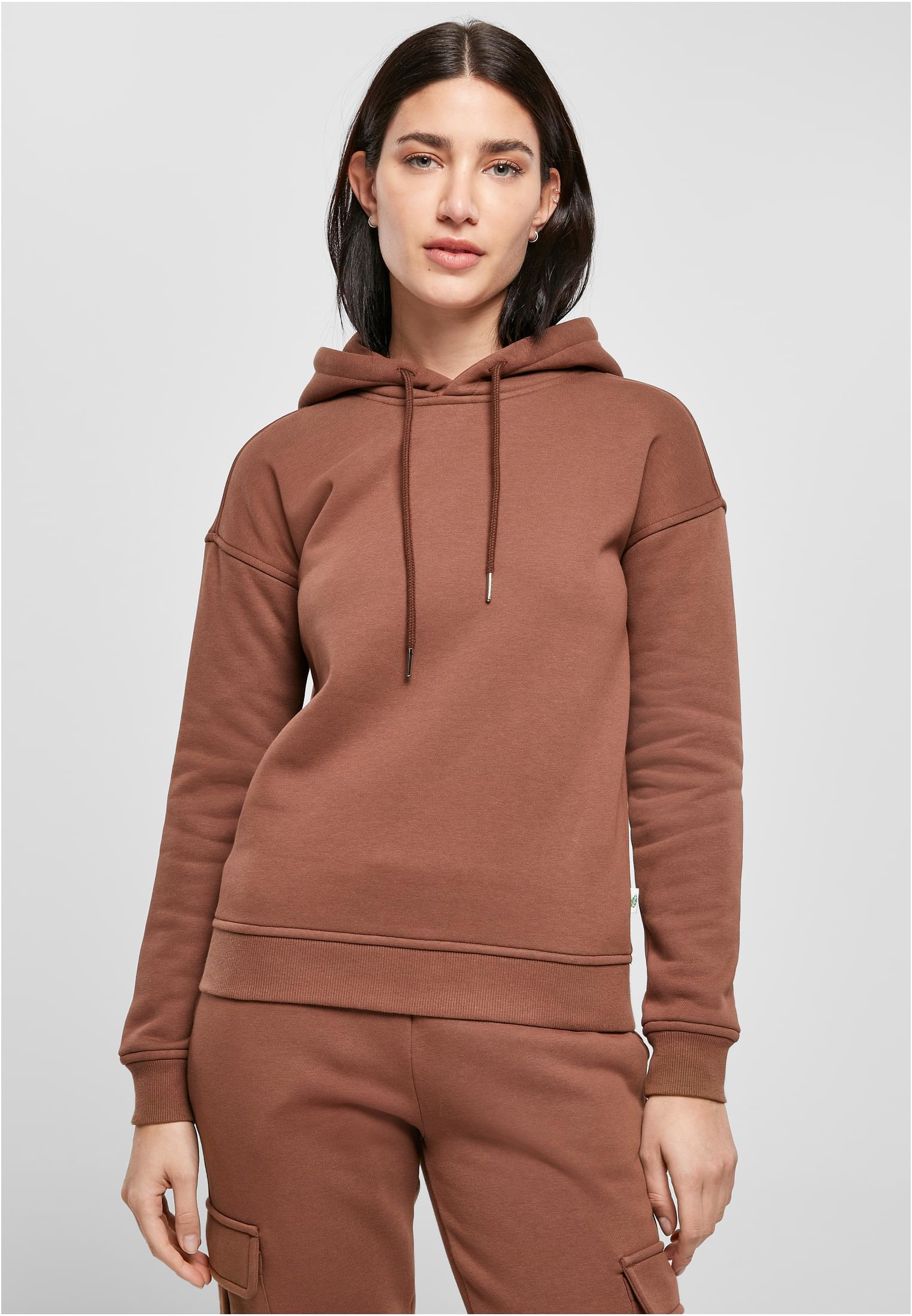 En kvinna som bär en brun UC Ladies Organic Hoody med matchande byxor, fotograferad framifrån.