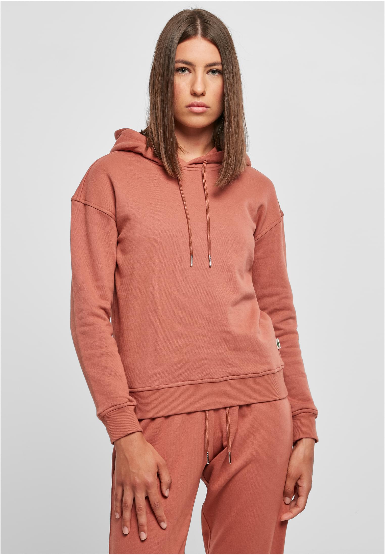 Frontbild av en kvinna som bär den dammrosa huvtröjan UC Ladies Organic Hoody.