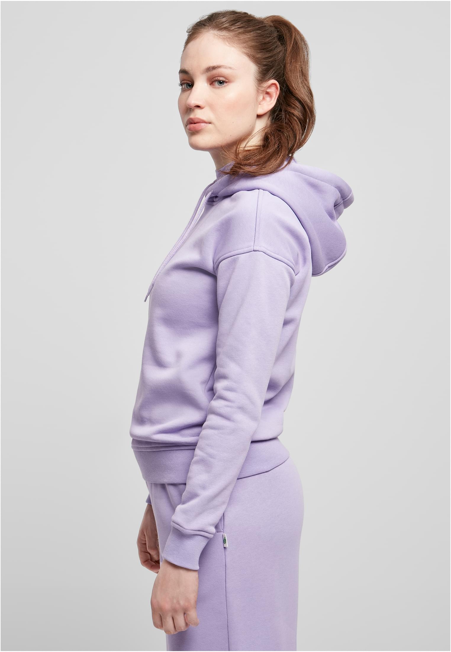 Sidovy av en kvinna som bär en ljuslila Ladies Organic Hoody.