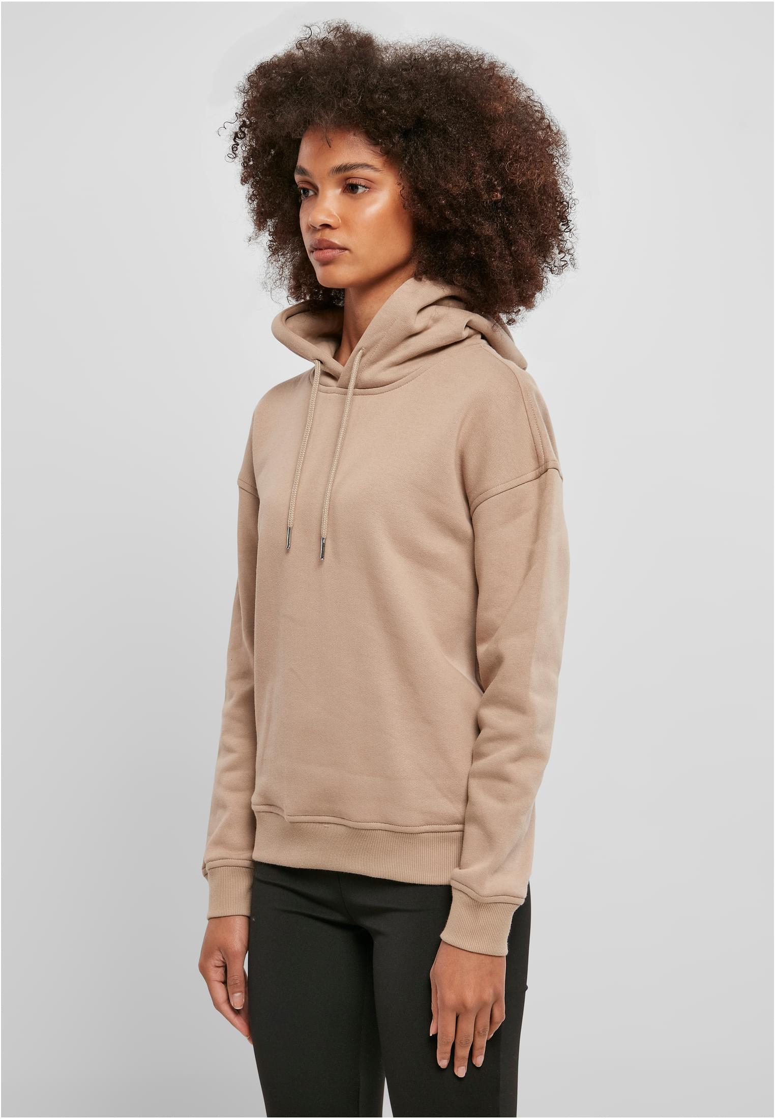 Kvinna fotograferad från sidan i en beige UC Ladies Organic Hoody.