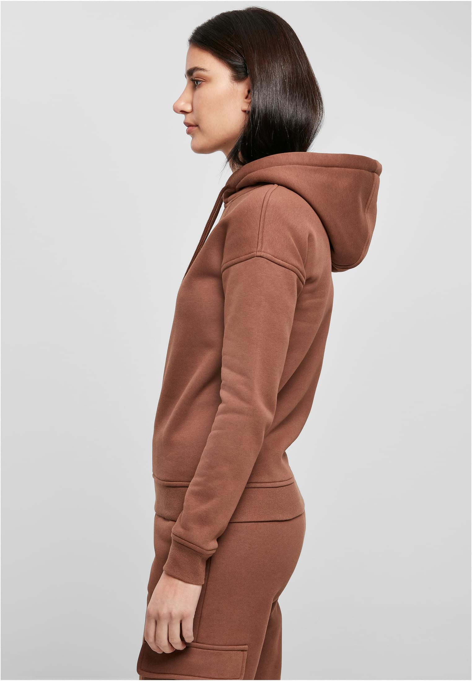 Kvinna i profil som bär den bruna UC Ladies Organic Hoody mot en grå bakgrund.