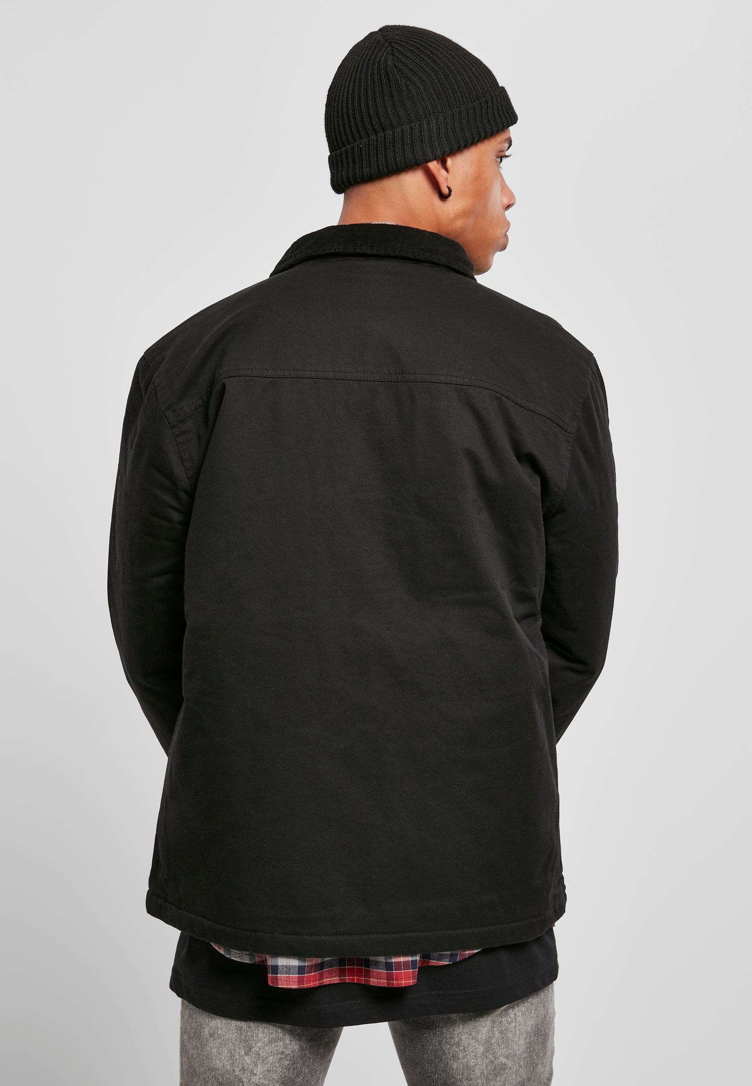 Baksidan av en man som bär en svart UC Hunter Jacket och en svart mössa.