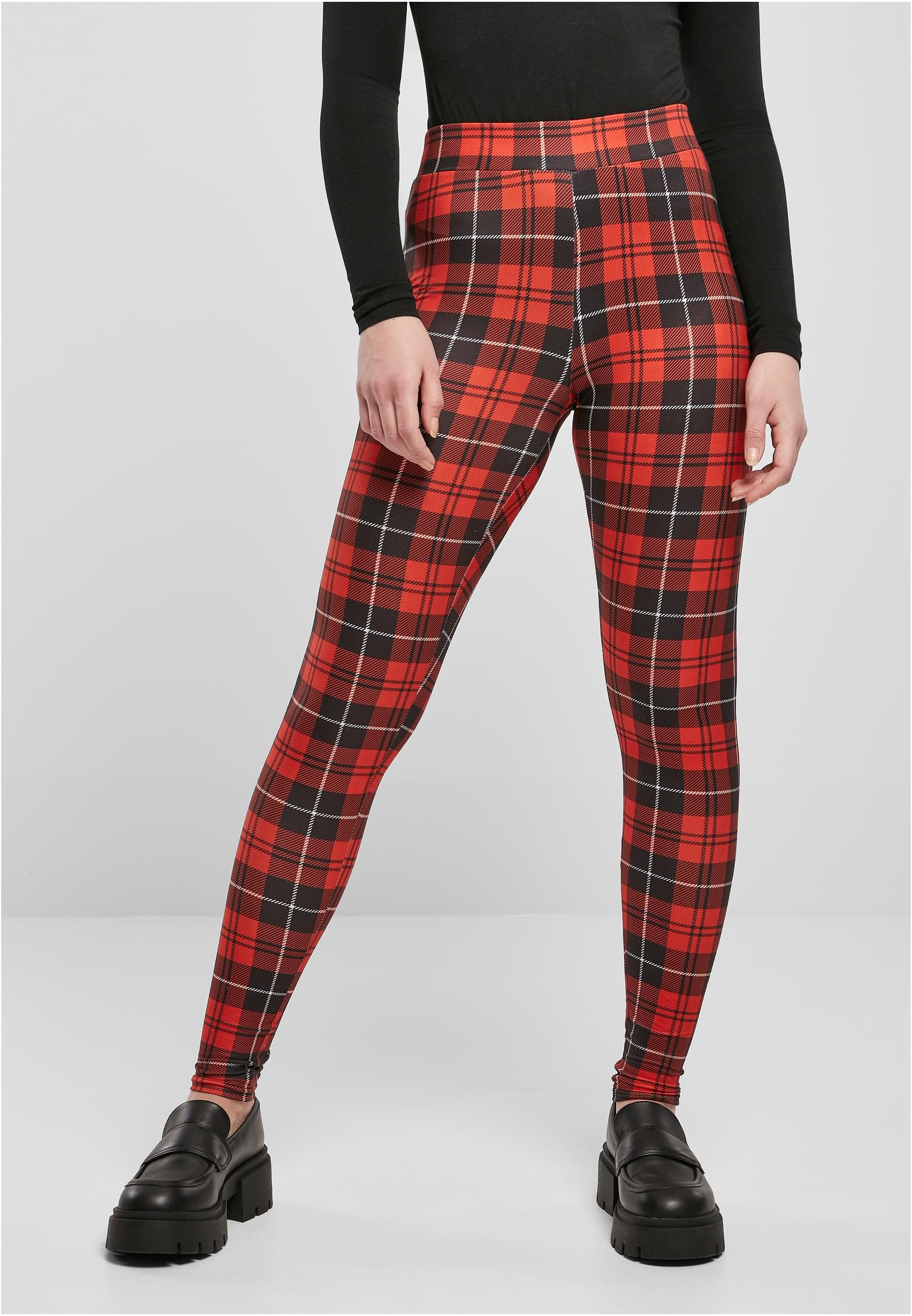 En modell poserar i ett par röd- och svartrutiga Ladies Soft AOP Leggings, stylade med en svart långärmad tröja och svarta loafers.