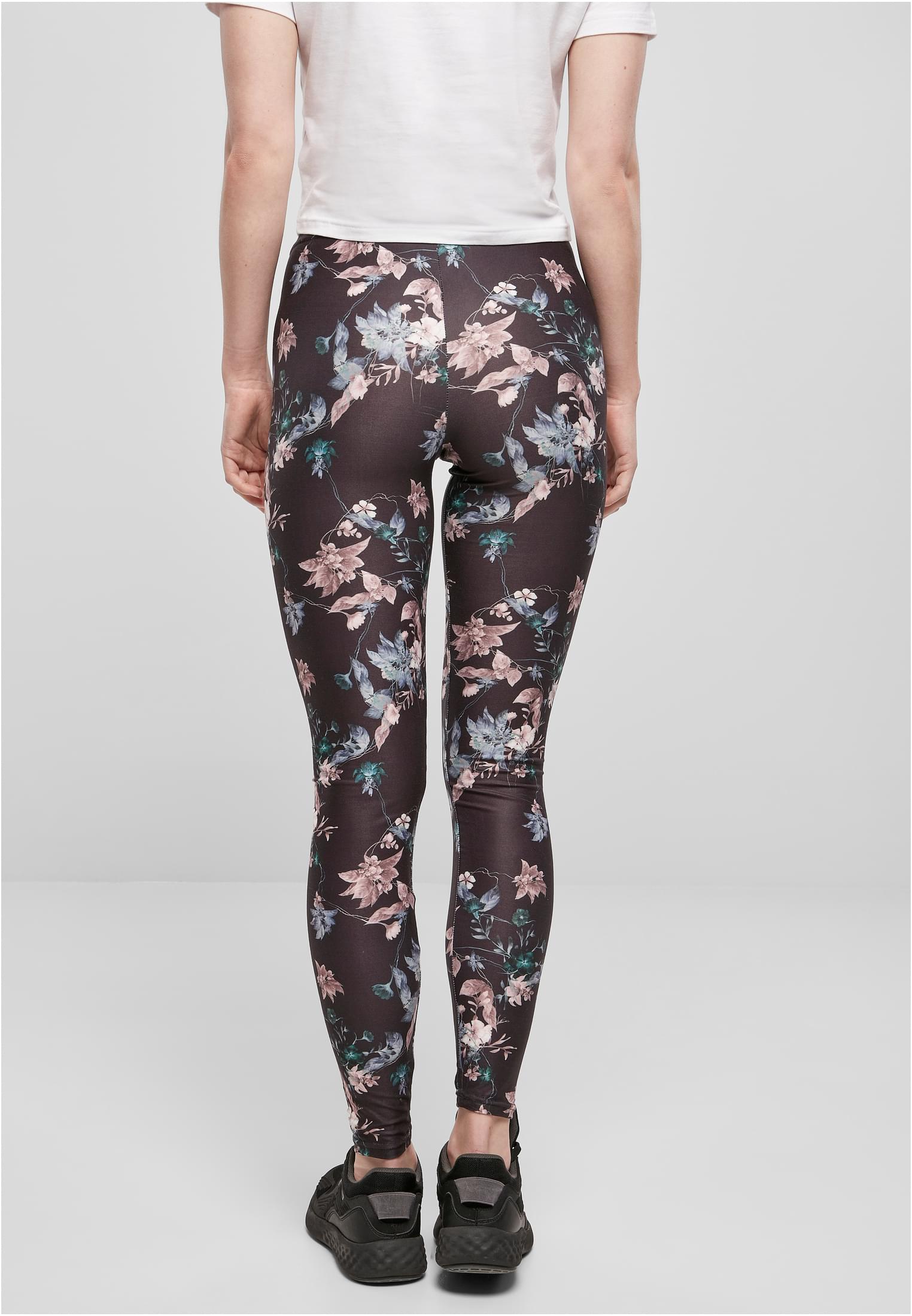 En kvinna sedd bakifrån, klädd i svarta, blommönstrade Ladies Soft AOP Leggings.