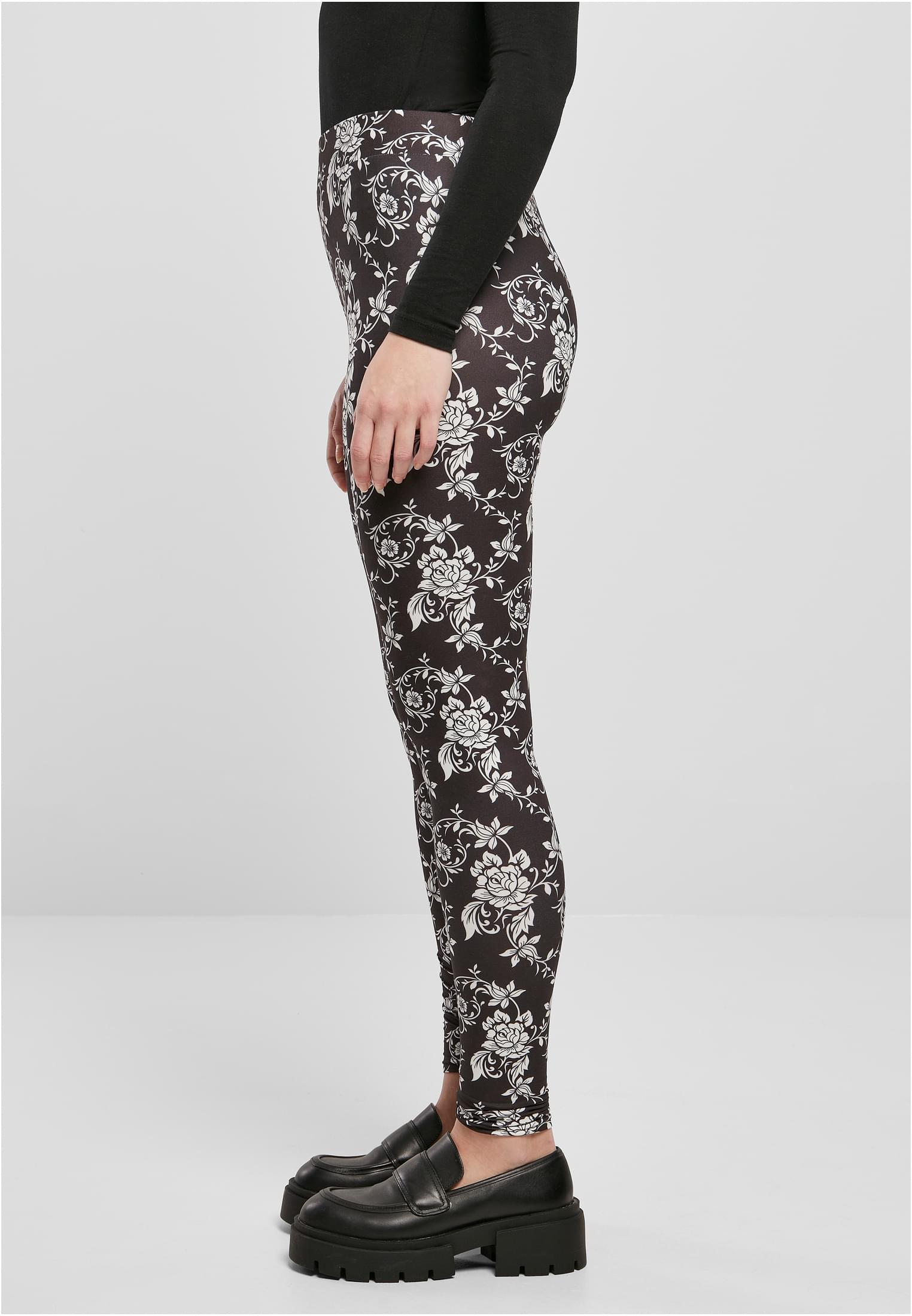 En kvinna sedd från sidan som bär UC Ladies Soft AOP Leggings i svart med ett vitt, blommigt allover-tryck.