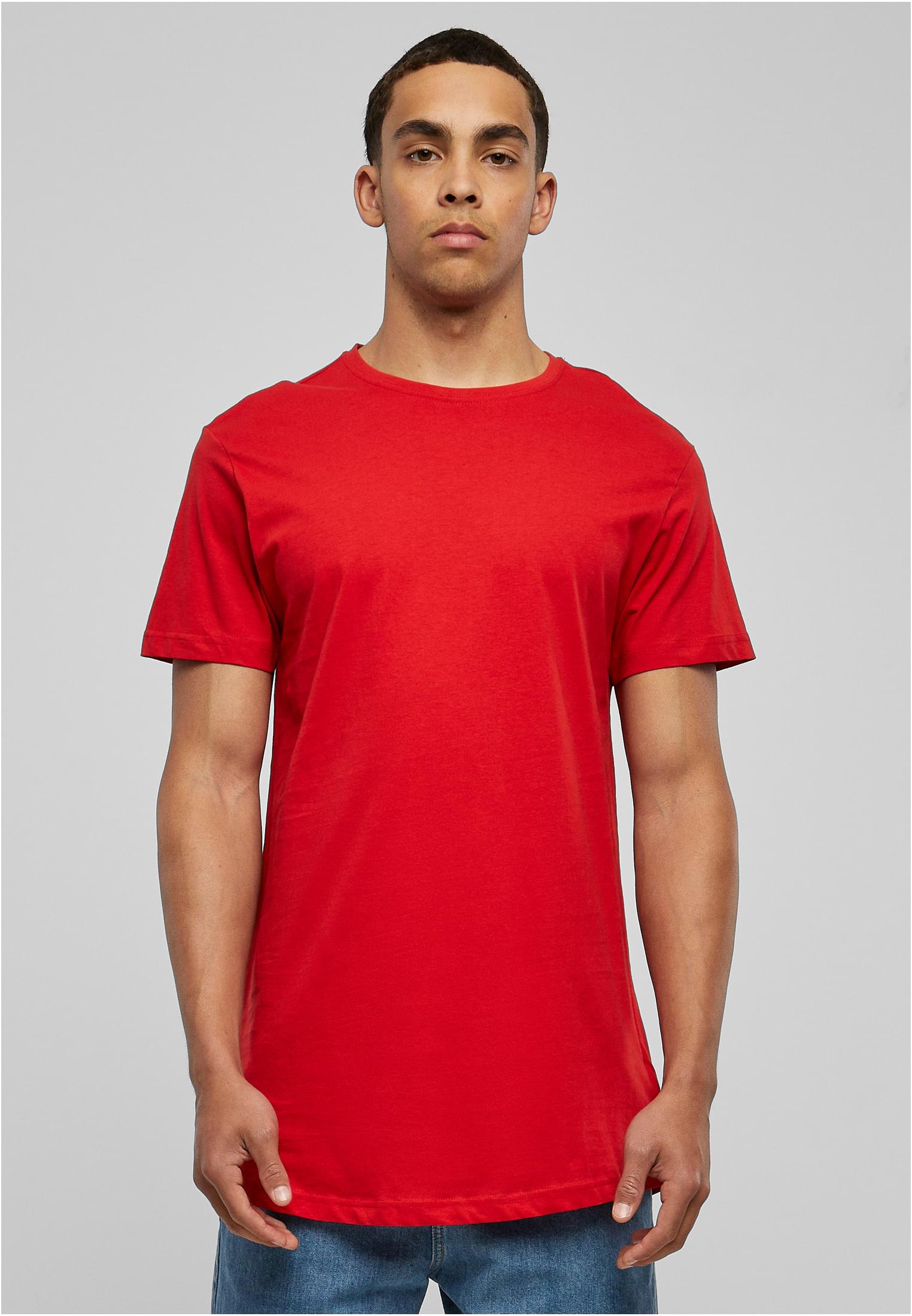 En manlig modell poserar framifrån i en röd, lång t-shirt med rundad nederkant mot en ljusgrå bakgrund.