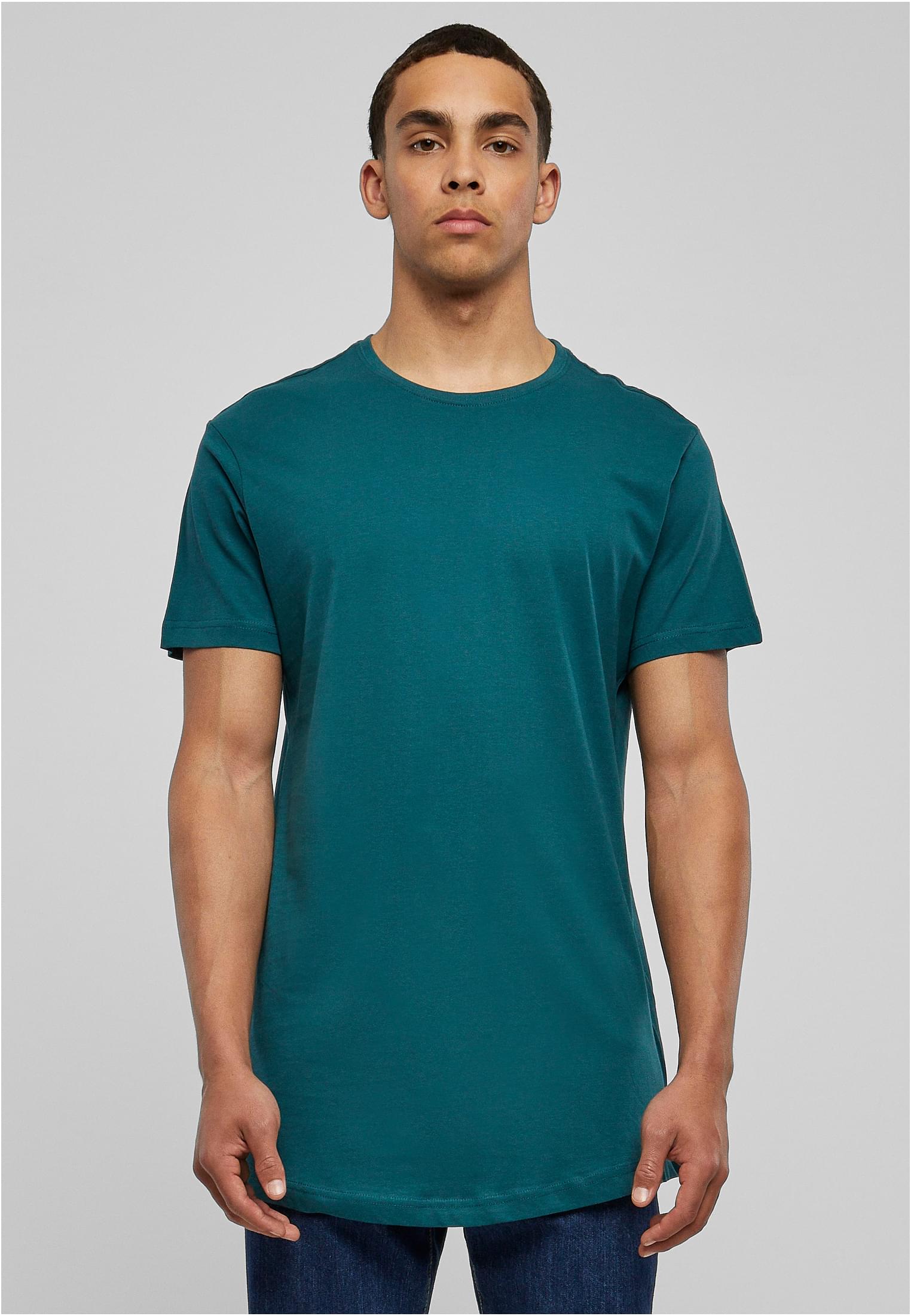 Frontvy av en man som bär en petrolfärgad UC Shaped Long Tee mot en ljusgrå bakgrund.