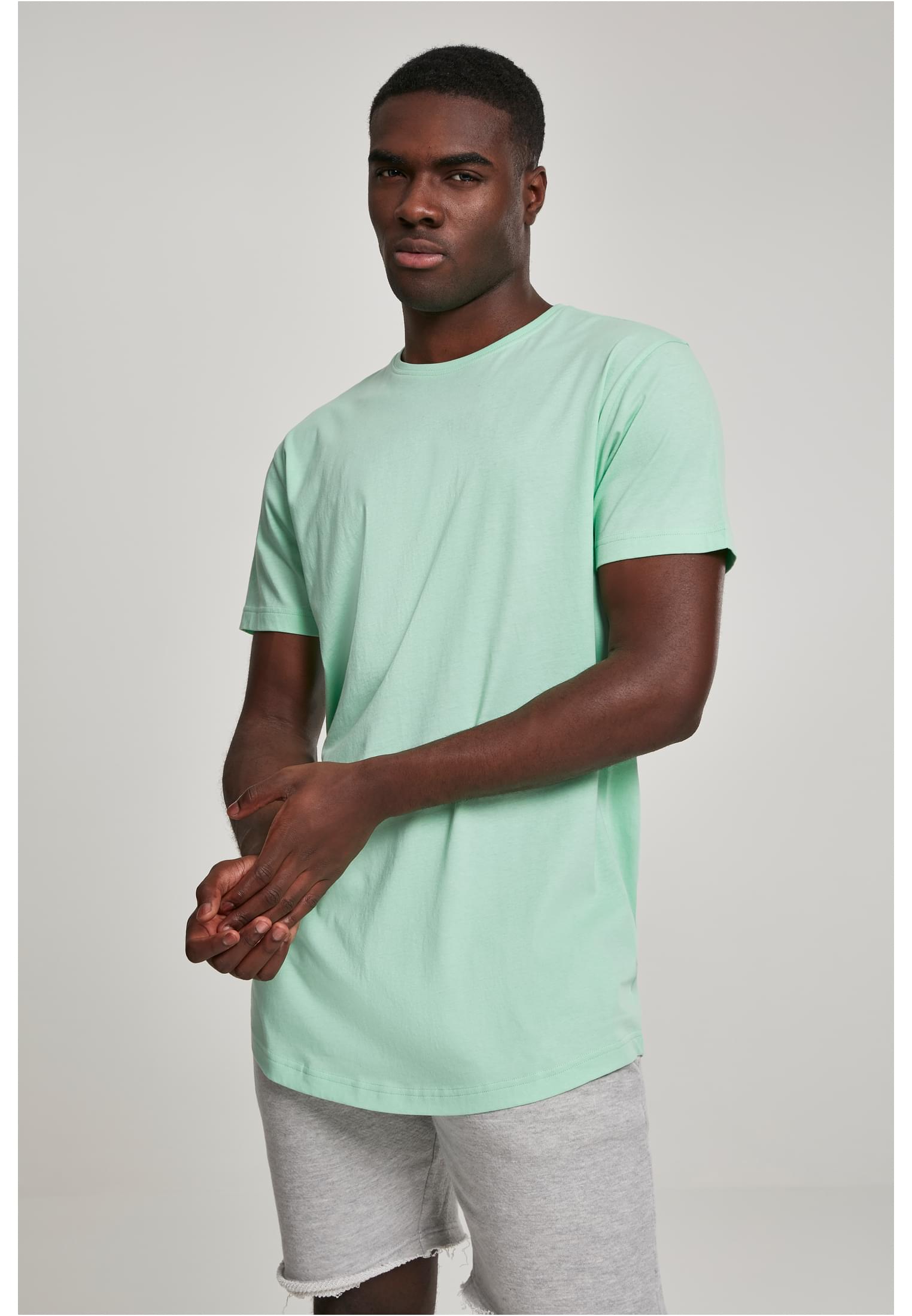 En manlig modell som bär en ljusgrön UC Shaped Long Tee t-shirt med rundad fåll.