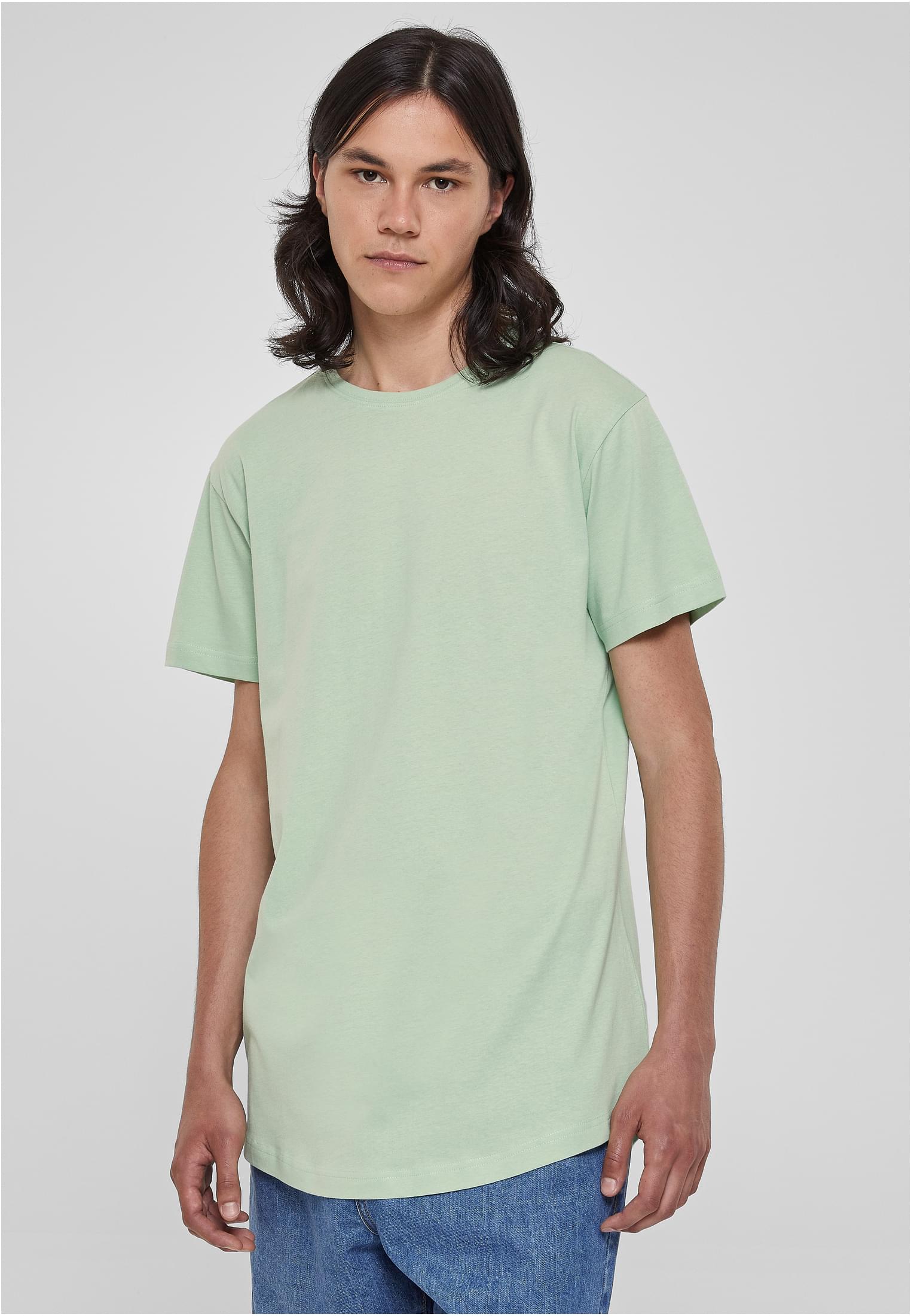 Manlig modell sedd framifrån i en ljusgrön UC Shaped Long Tee t-shirt.