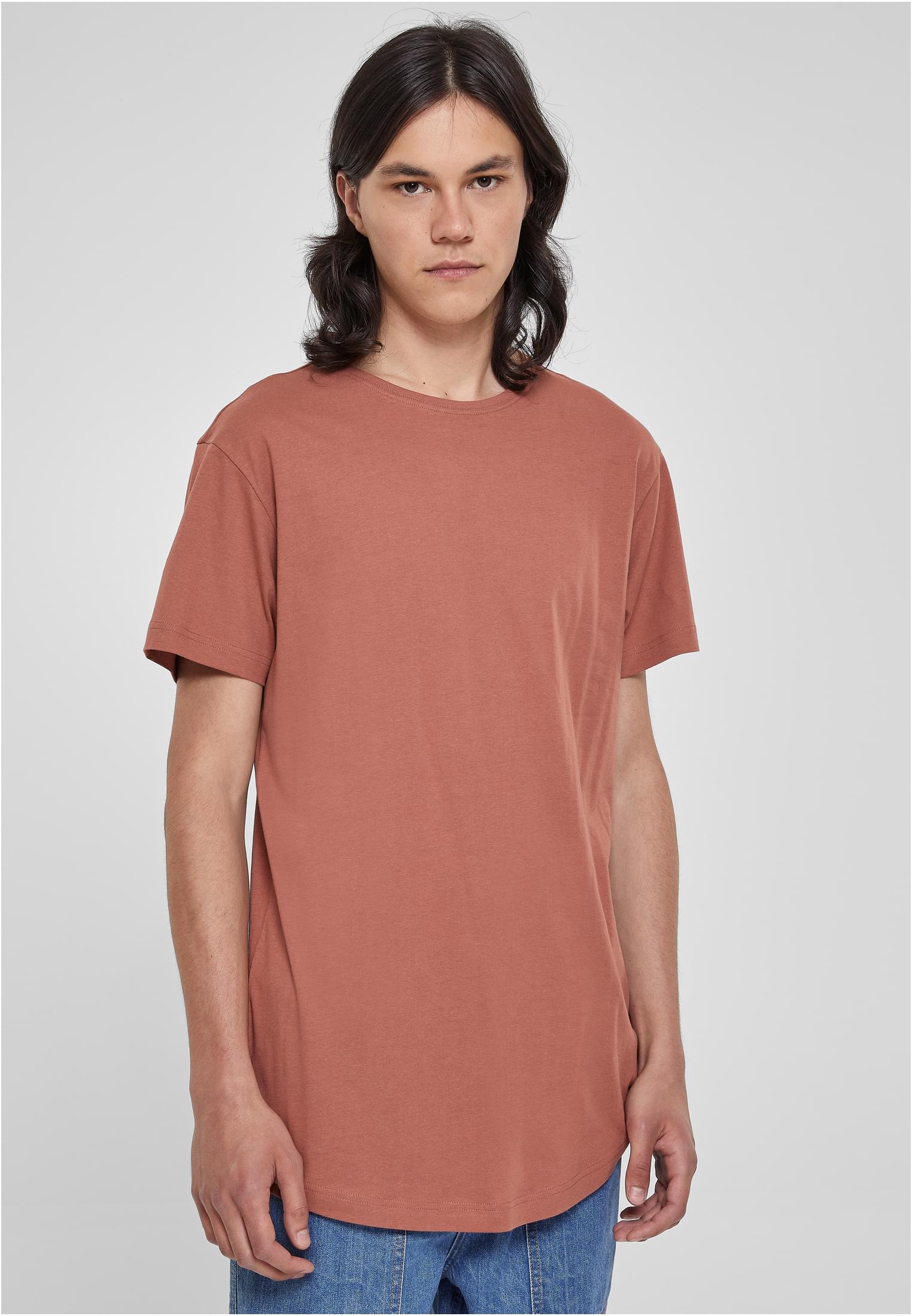 Frontvy av en manlig modell med långt hår som bär en terrakottafärgad UC Shaped Long Tee.