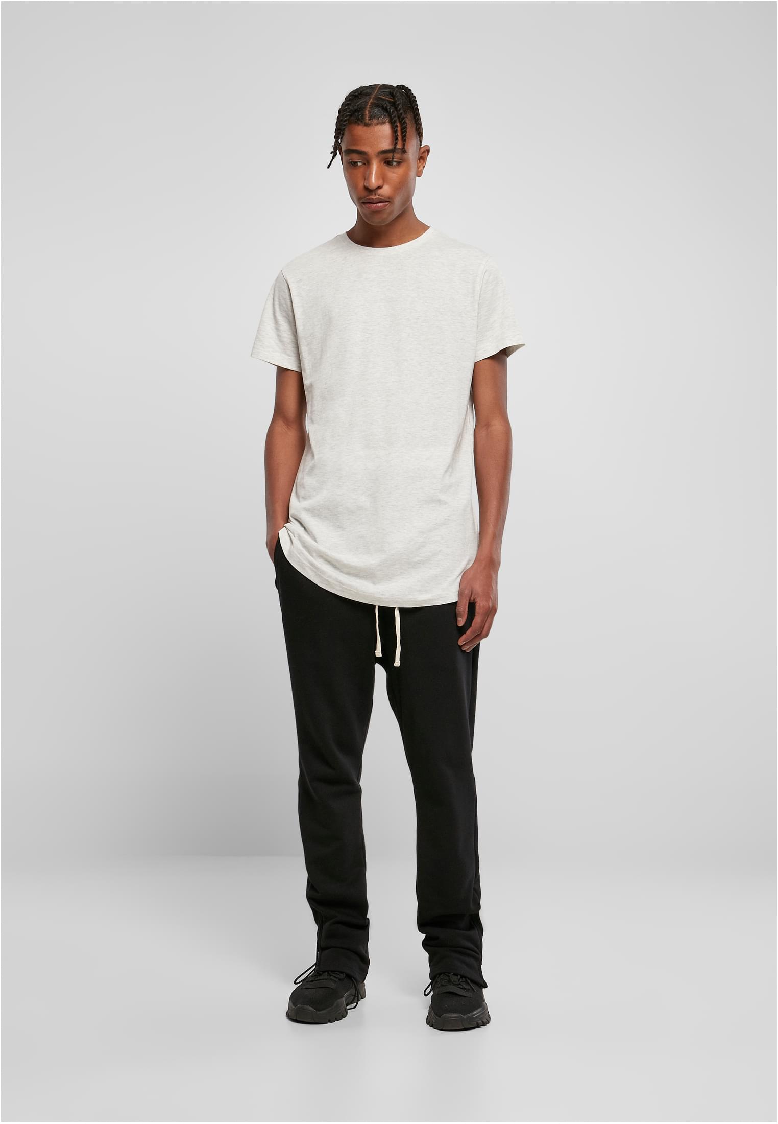 Manlig modell som bär en ljusgrå Shaped Long Tee och svarta byxor.