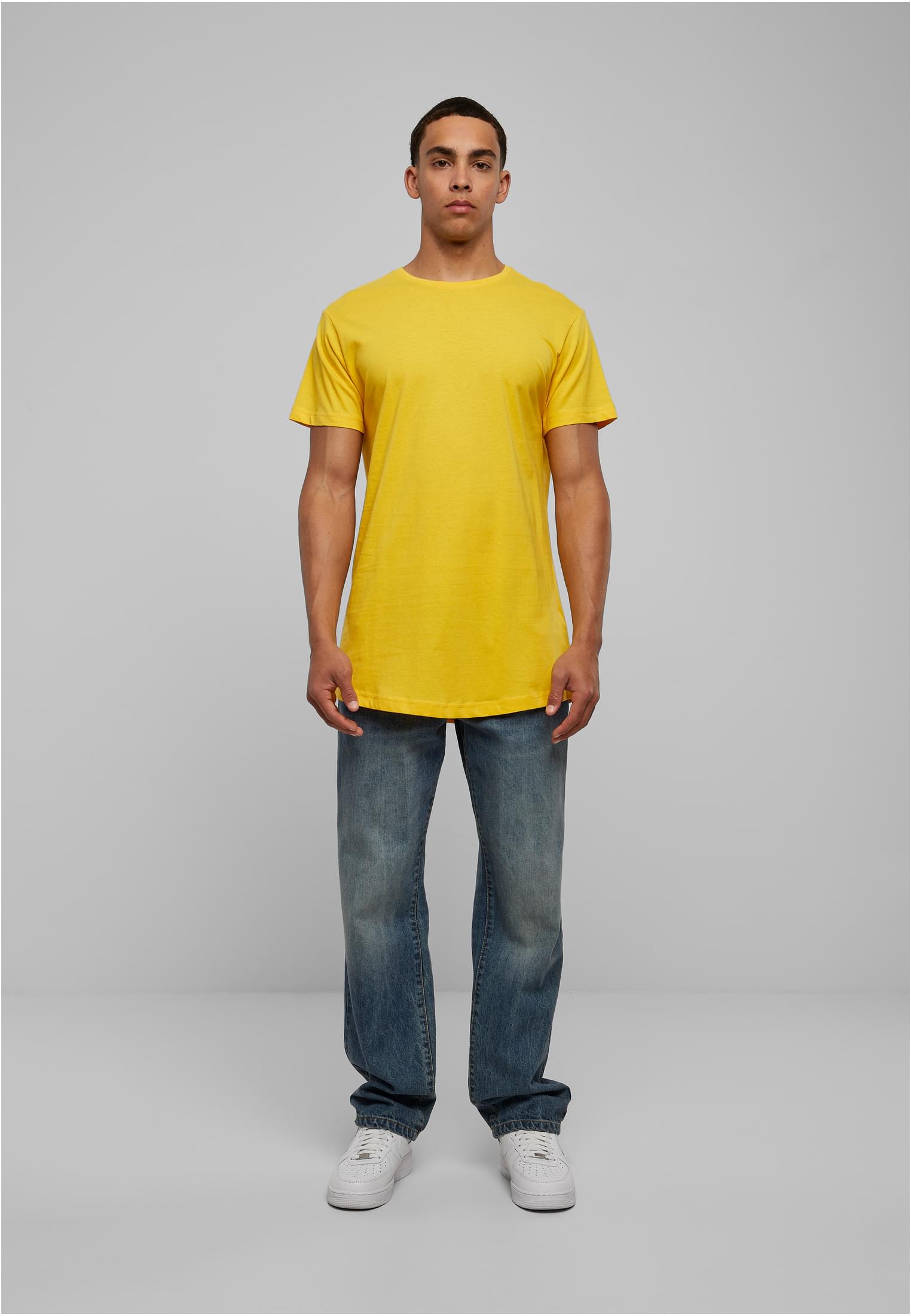 Manlig modell som bär den gula t-shirten Shaped Long Tee, stylad med blåa jeans och vita sneakers.