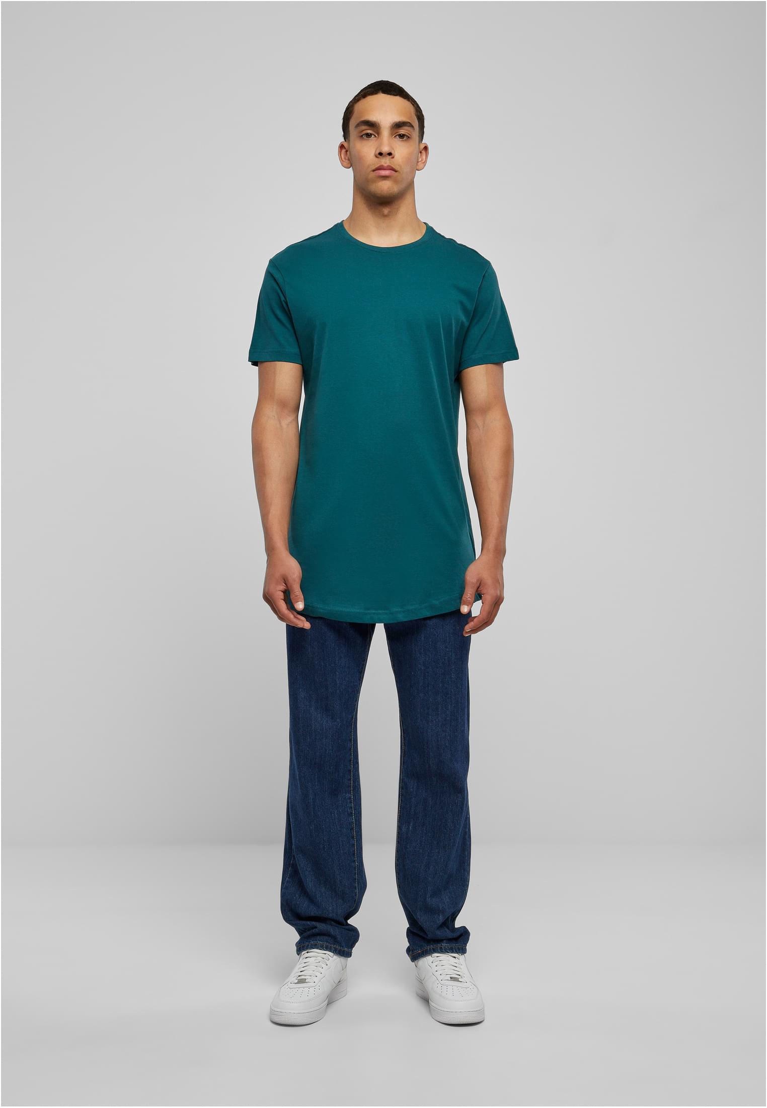 Manlig modell som bär en grönblå UC Shaped Long Tee, mörkblå jeans och vita sneakers, fotograferad framifrån.