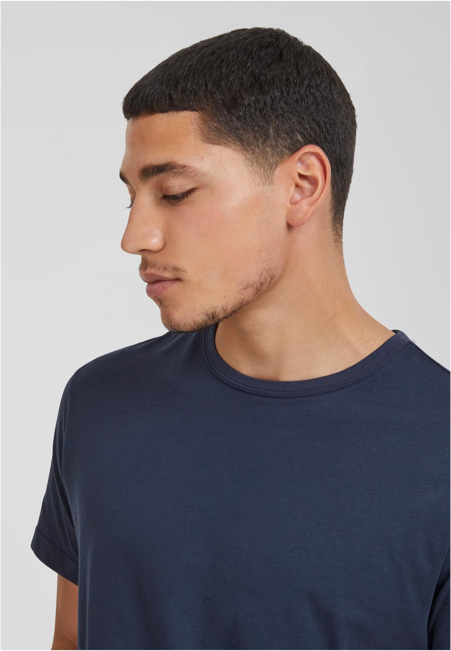 Närbild på en man i profil som bär en mörkblå Urban Classics Shaped Long Tee.