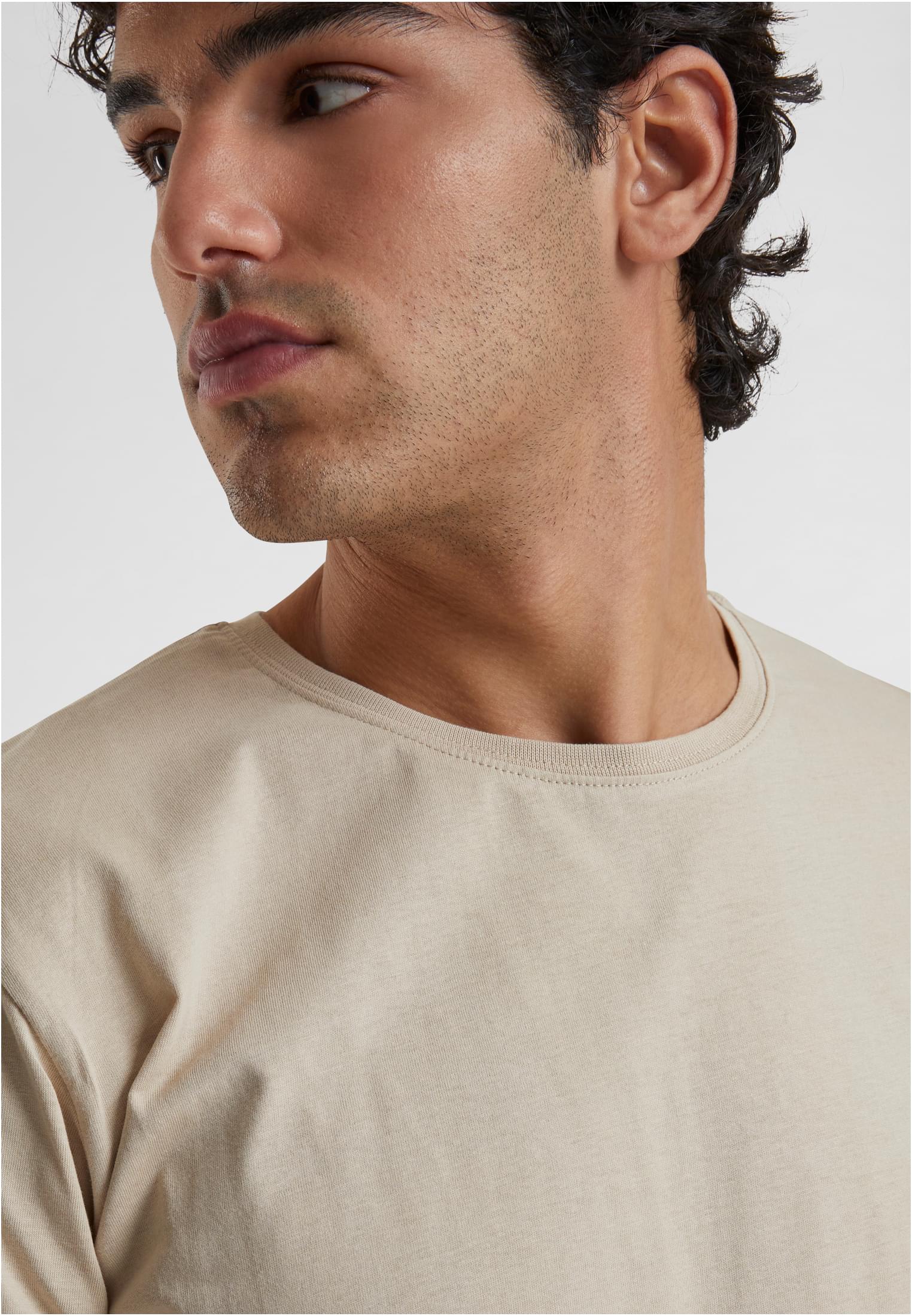Närbild på en man som bär en beige Shaped Long Tee, som visar t-shirtens halsringning och mannens profil.