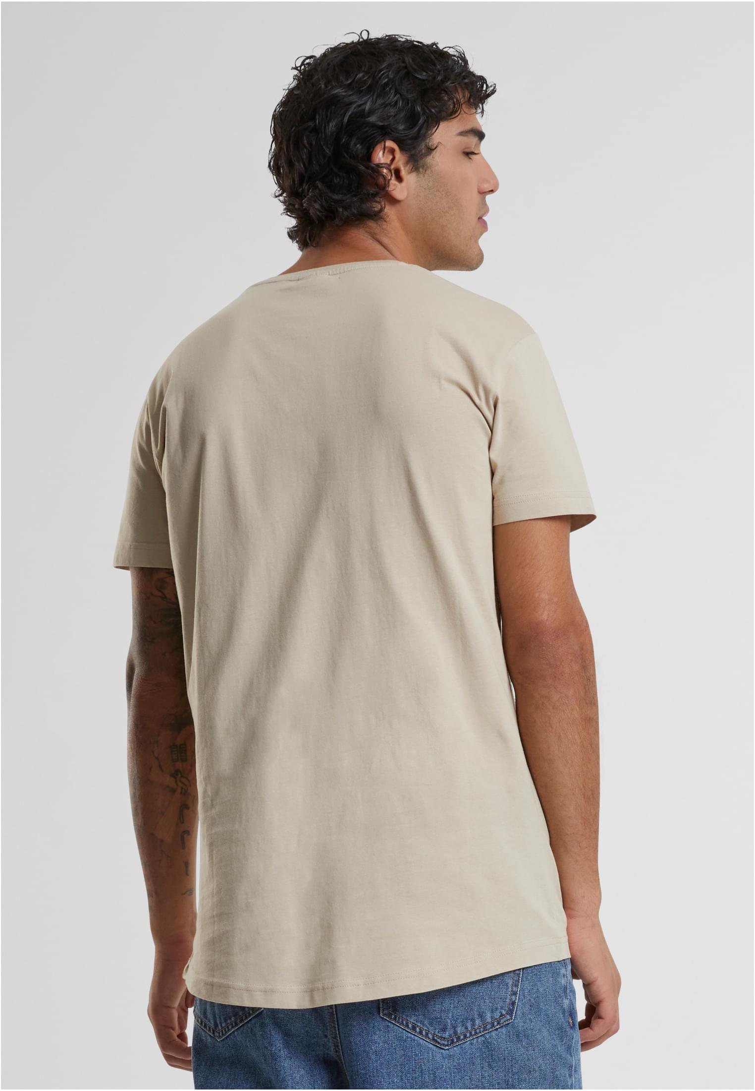 Baksida av en man som bär en terracottafärgad Shaped Long Tee med rundad fåll och blåjeans.