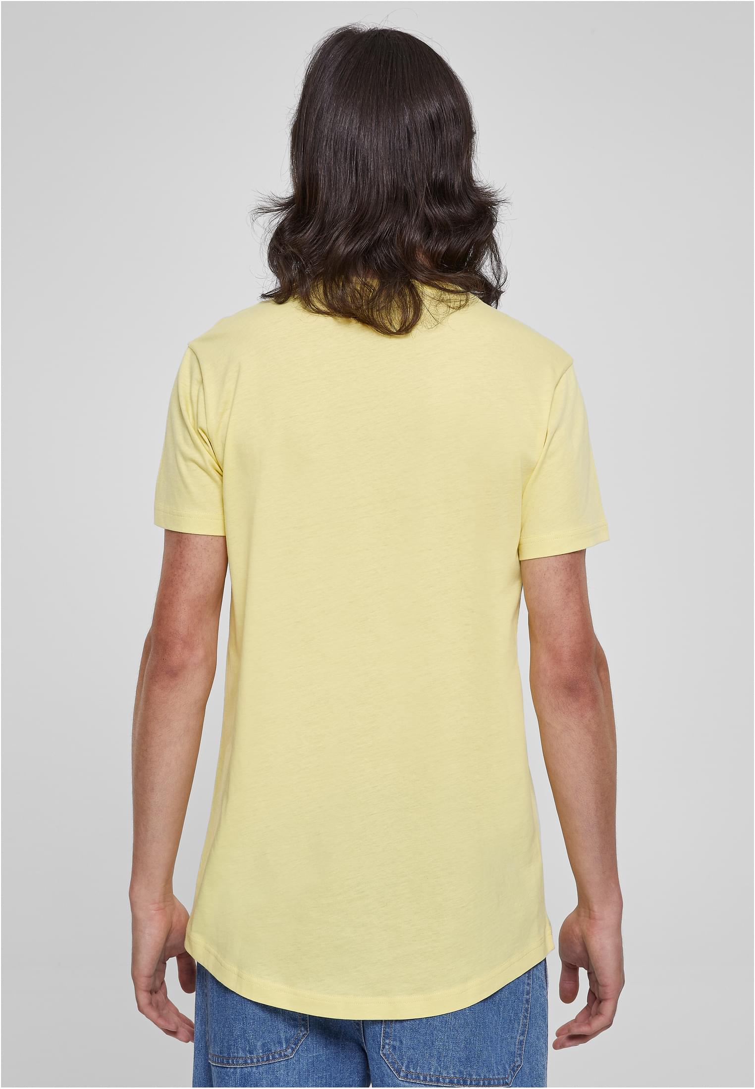 Baksidan av en man som bär en ljusgul Urban Classics Shaped Long Tee, vilket visar t-shirtens längre passform och rundade fåll.