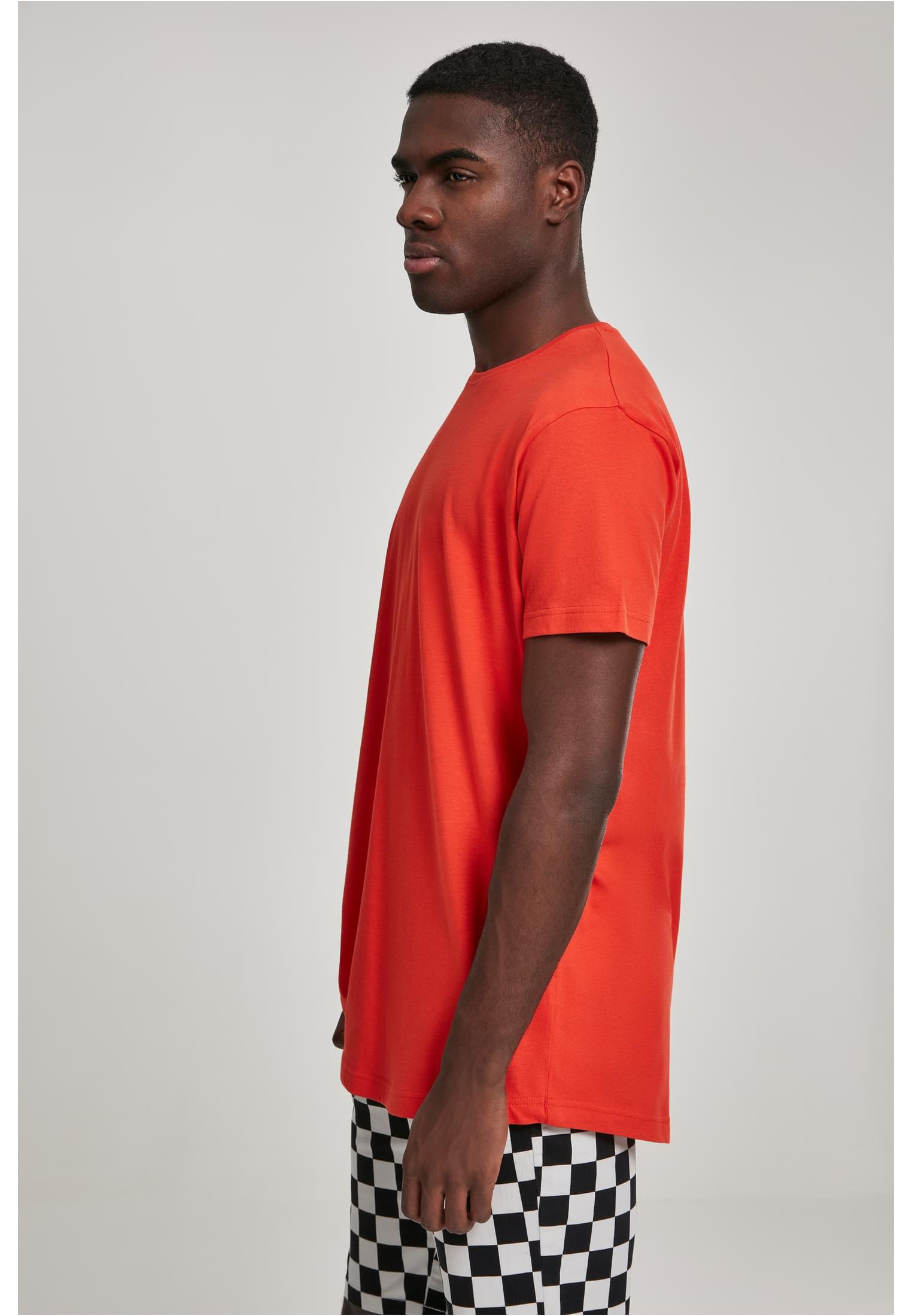 Man i sidoprofil som bär en terrakottafärgad Shaped Long Tee och schackrutiga shorts.