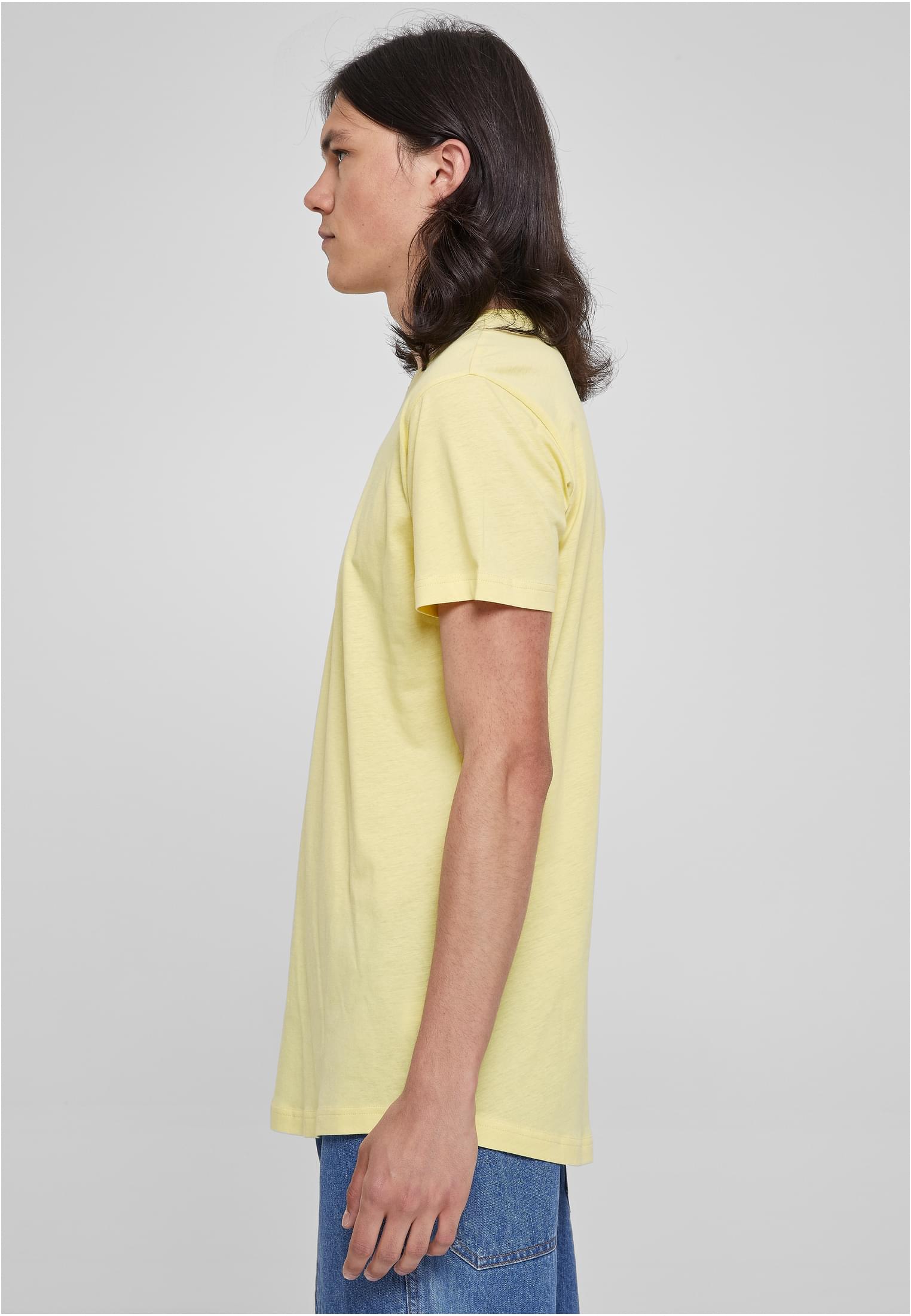 Sidovy av en manlig modell med långt hår som bär en ljusgul UC Shaped Long Tee-t-shirt mot en ljusgrå bakgrund.