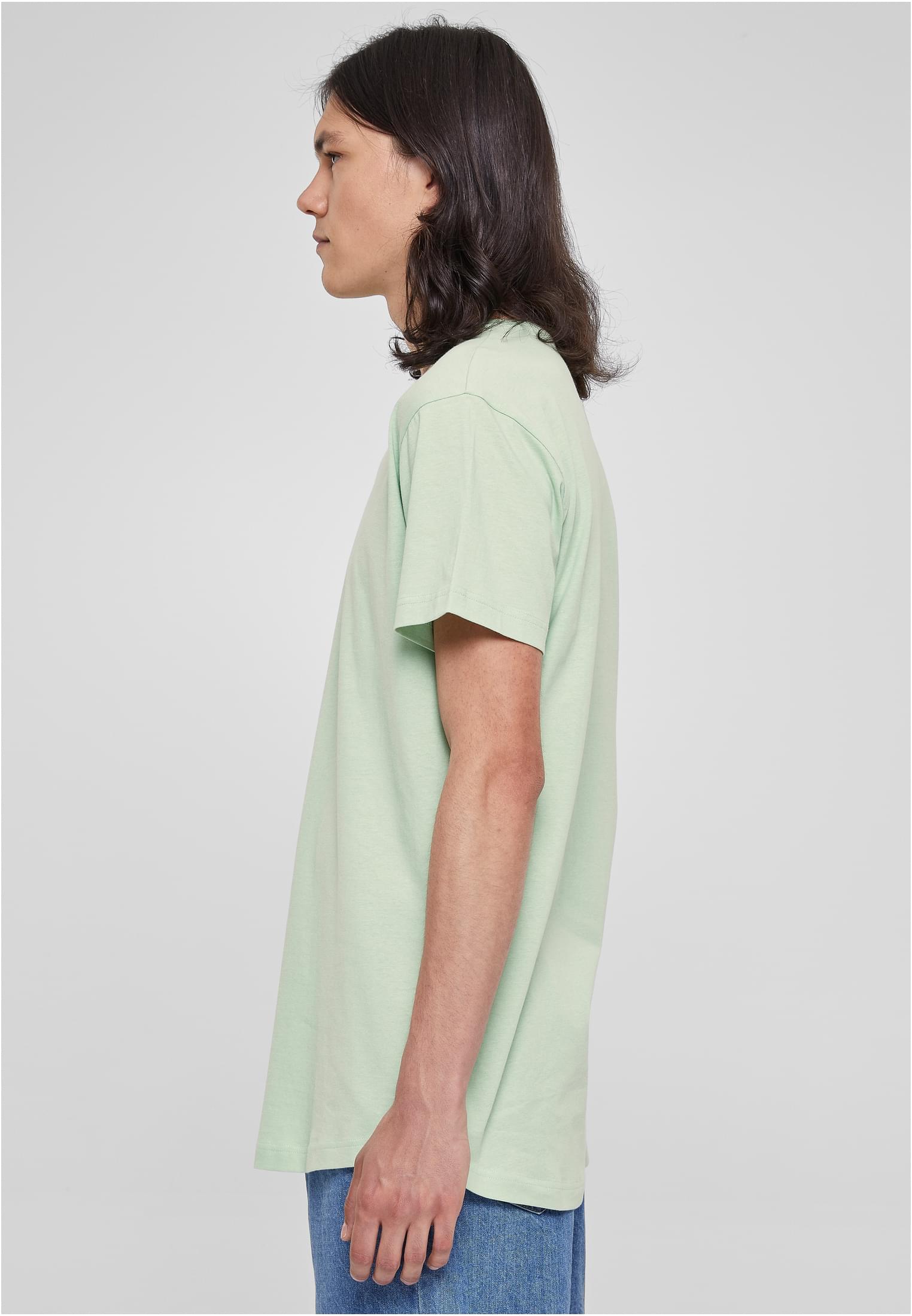 Sidovy av en manlig modell som bär en ljusgrön UC Shaped Long Tee mot en vit bakgrund.