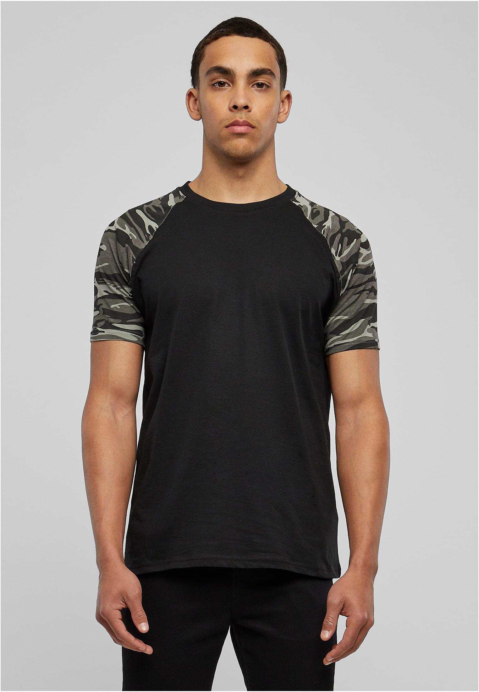 Man framifrån som bär en svart T-shirt med kamouflagemönstrade raglanärmar.