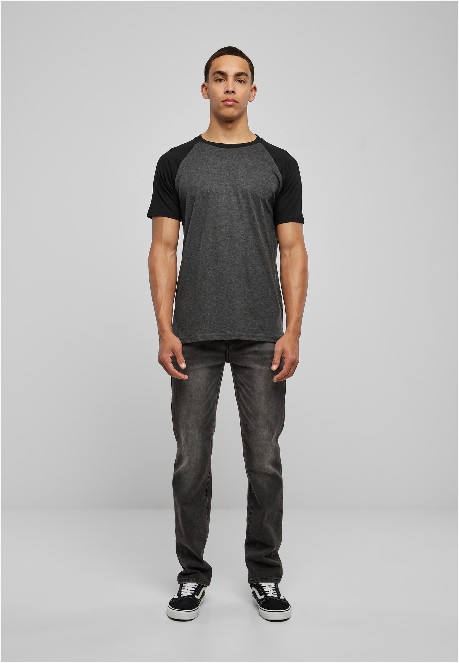 Manlig modell som visar framsidan av Raglan Contrast Tee. T-shirten är mörkgrå med svarta raglanärmar och är stylad med mörka jeans och sneakers.