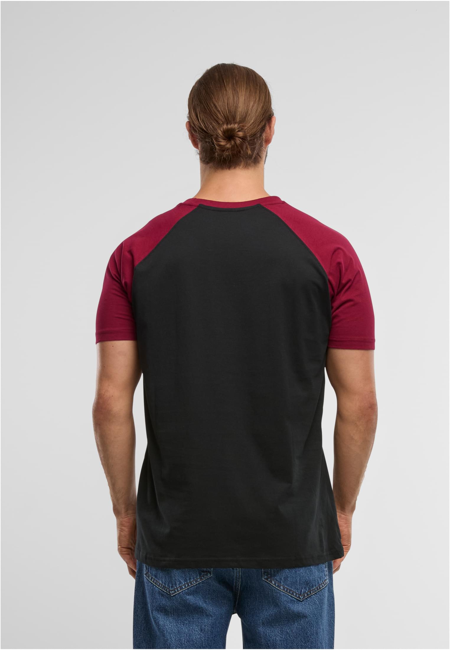 Man sedd bakifrån som bär en svart t-shirt med vinröda raglanärmar.