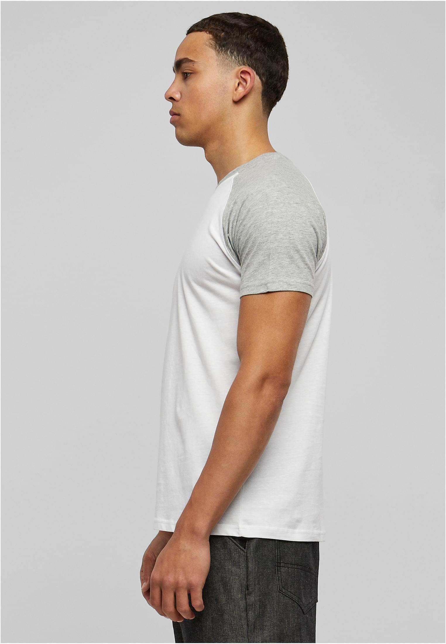 Sidovy av en man som bär en vit t-shirt med grå raglanärmar.