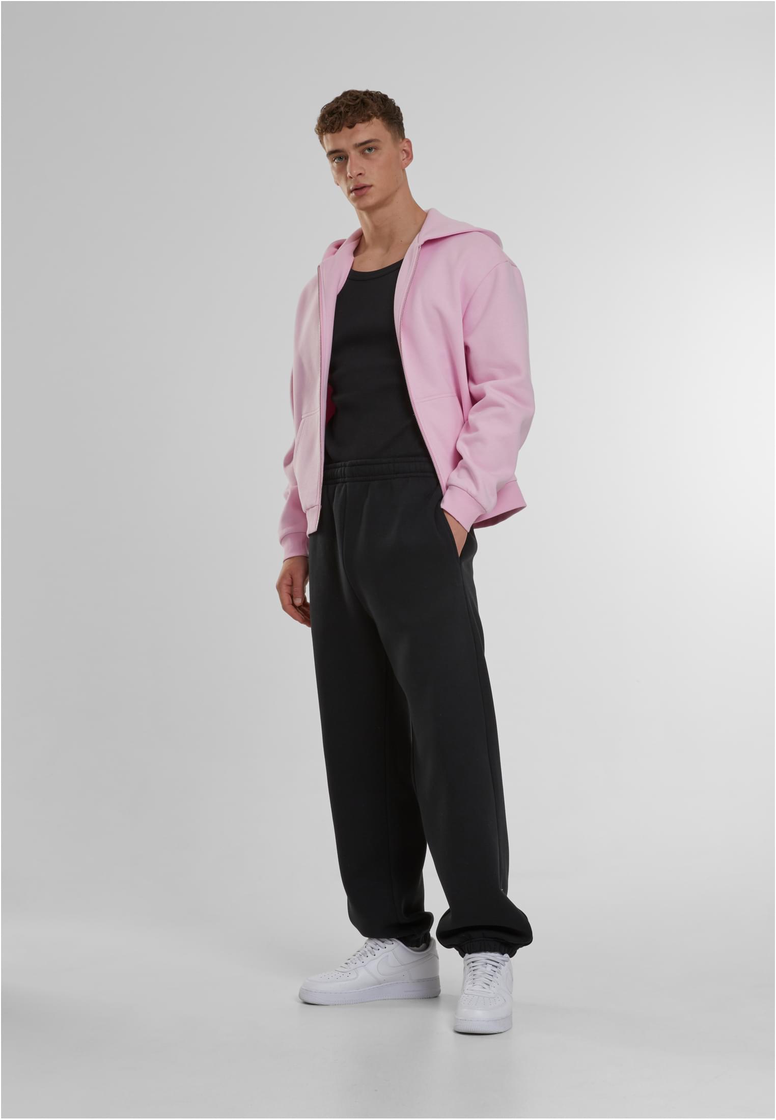 En manlig modell i Fluffy Sweatpants, svart linne och rosa huvtröja.
