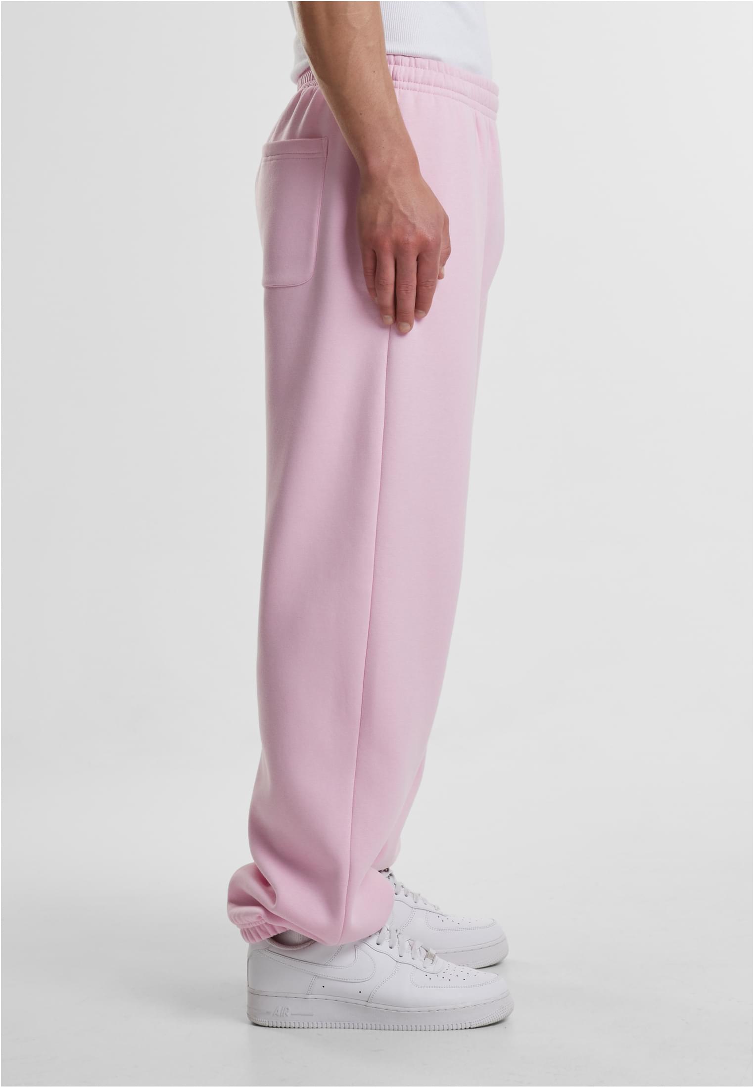 Sidovy av en man som bär ljuslila Fluffy Sweatpants och vita sneakers.