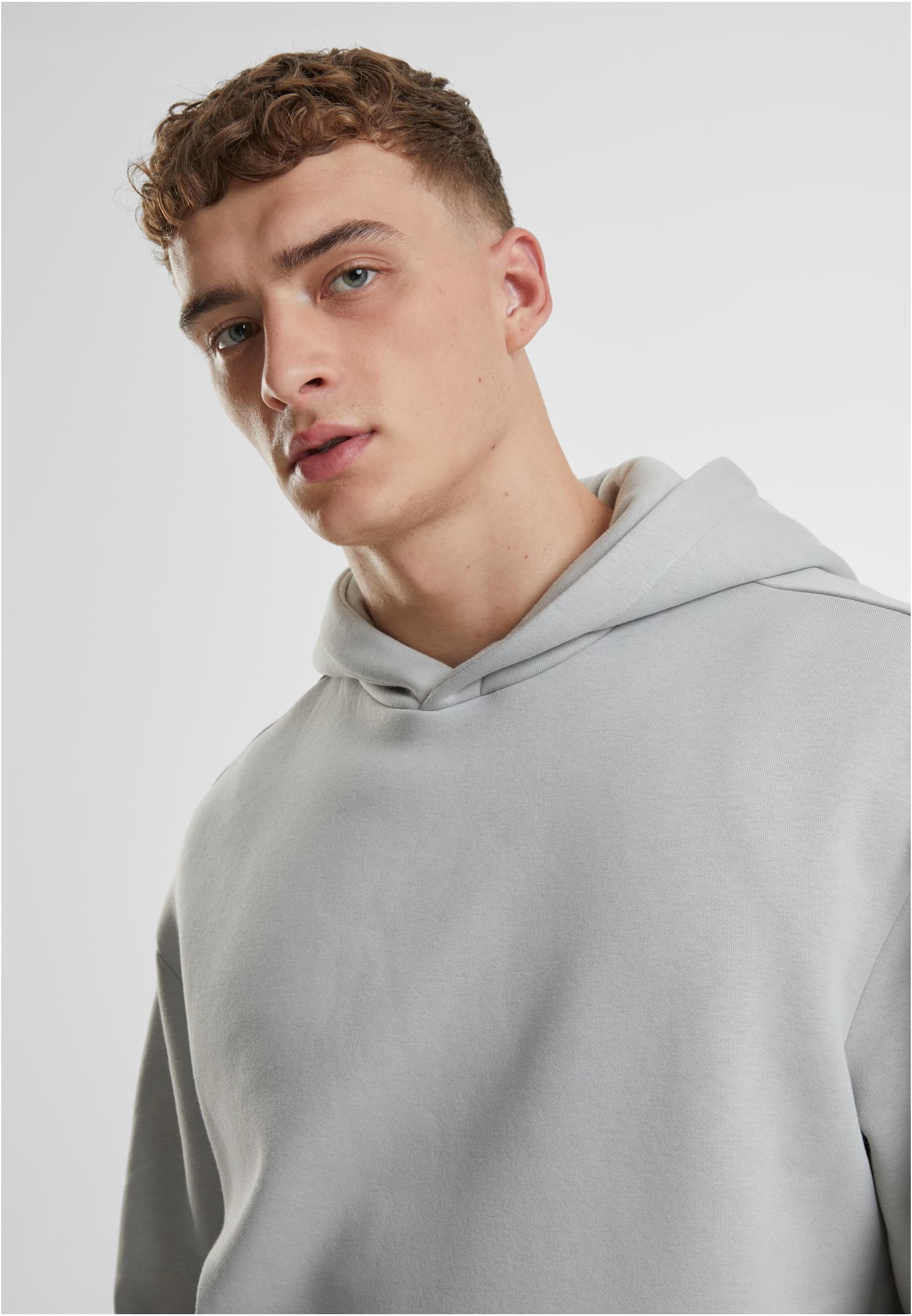 Närbild på en man med lockigt hår som bär en ljusgrå luvtröja.