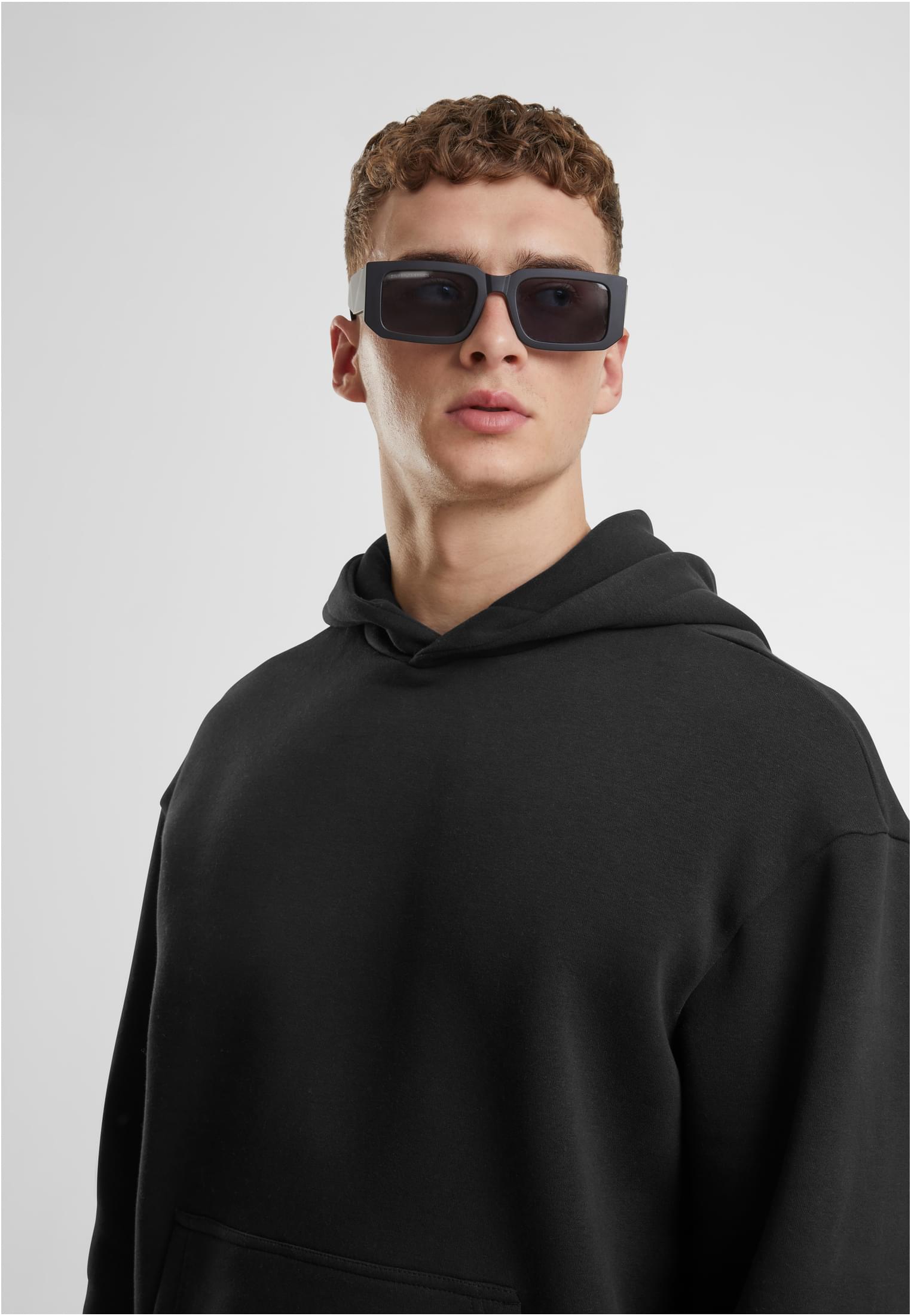 Närbild på en man som bär en svart UC Fluffy Hoody och solglasögon.