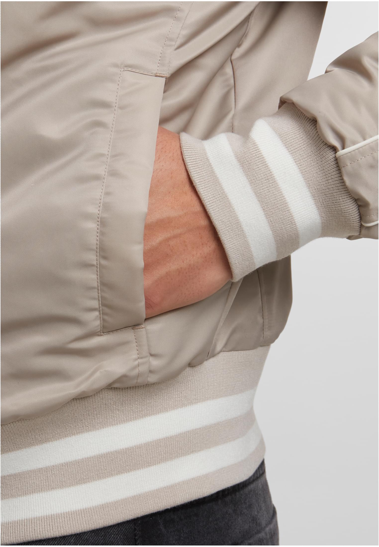 Närbild på fickan och den randiga mudden på den beiga UC Racer Bomber Jacket.