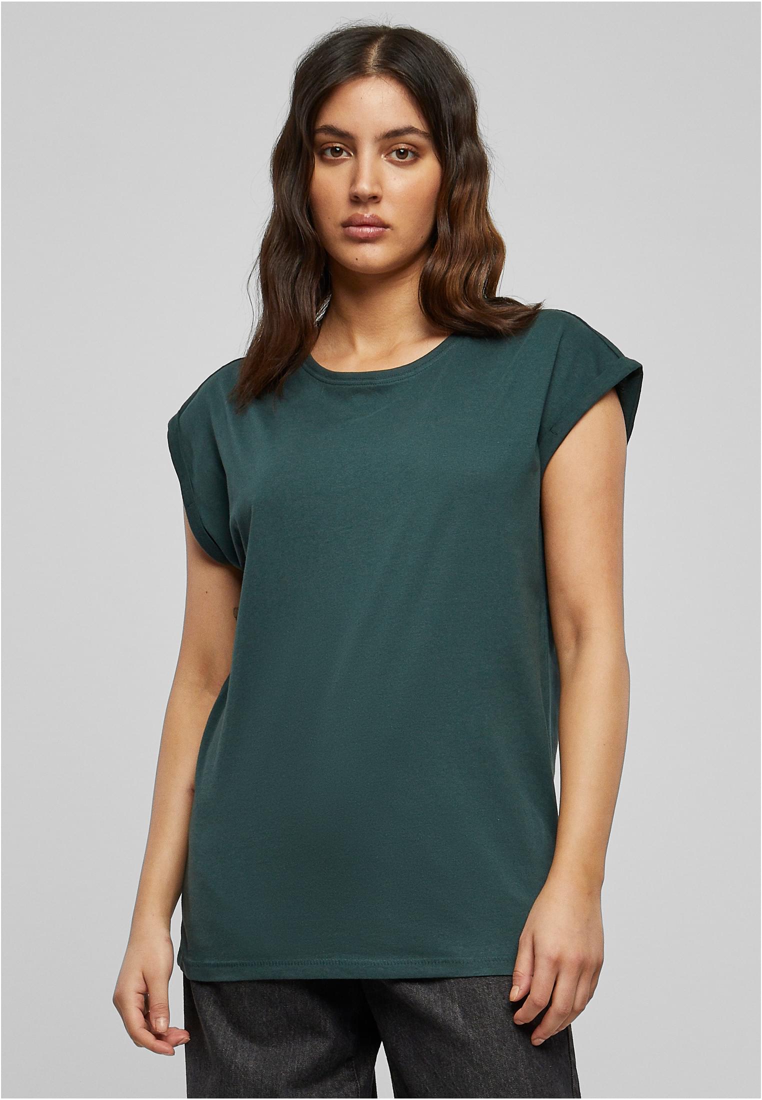 En kvinna som visar framsidan av en mörkgrön Ladies Extended Shoulder Tee, med nedhasade axlar och uppvikta ärmar.