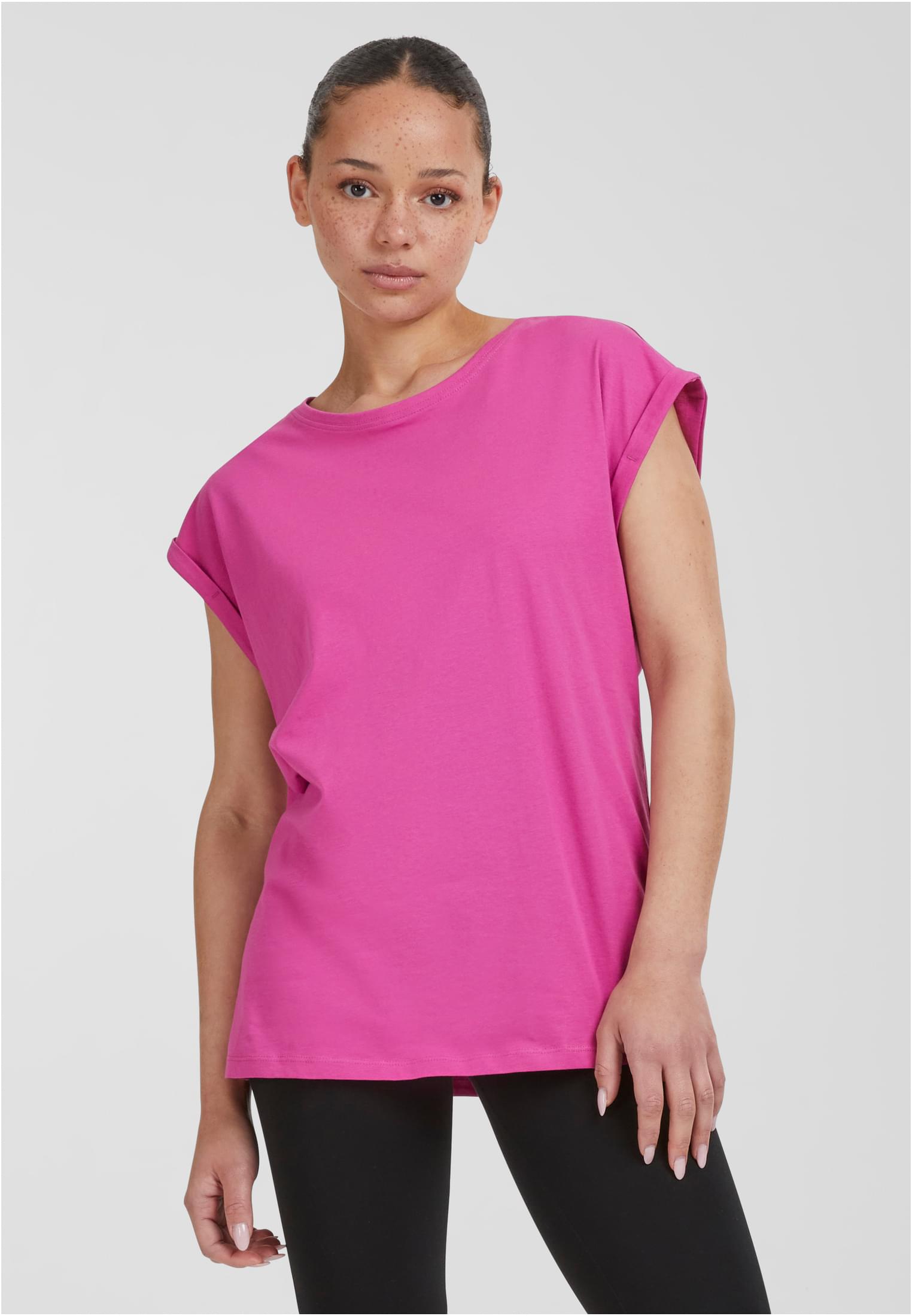 Kvinna som bär en rosa Ladies Extended Shoulder Tee från Urban Classics med svarta leggings.