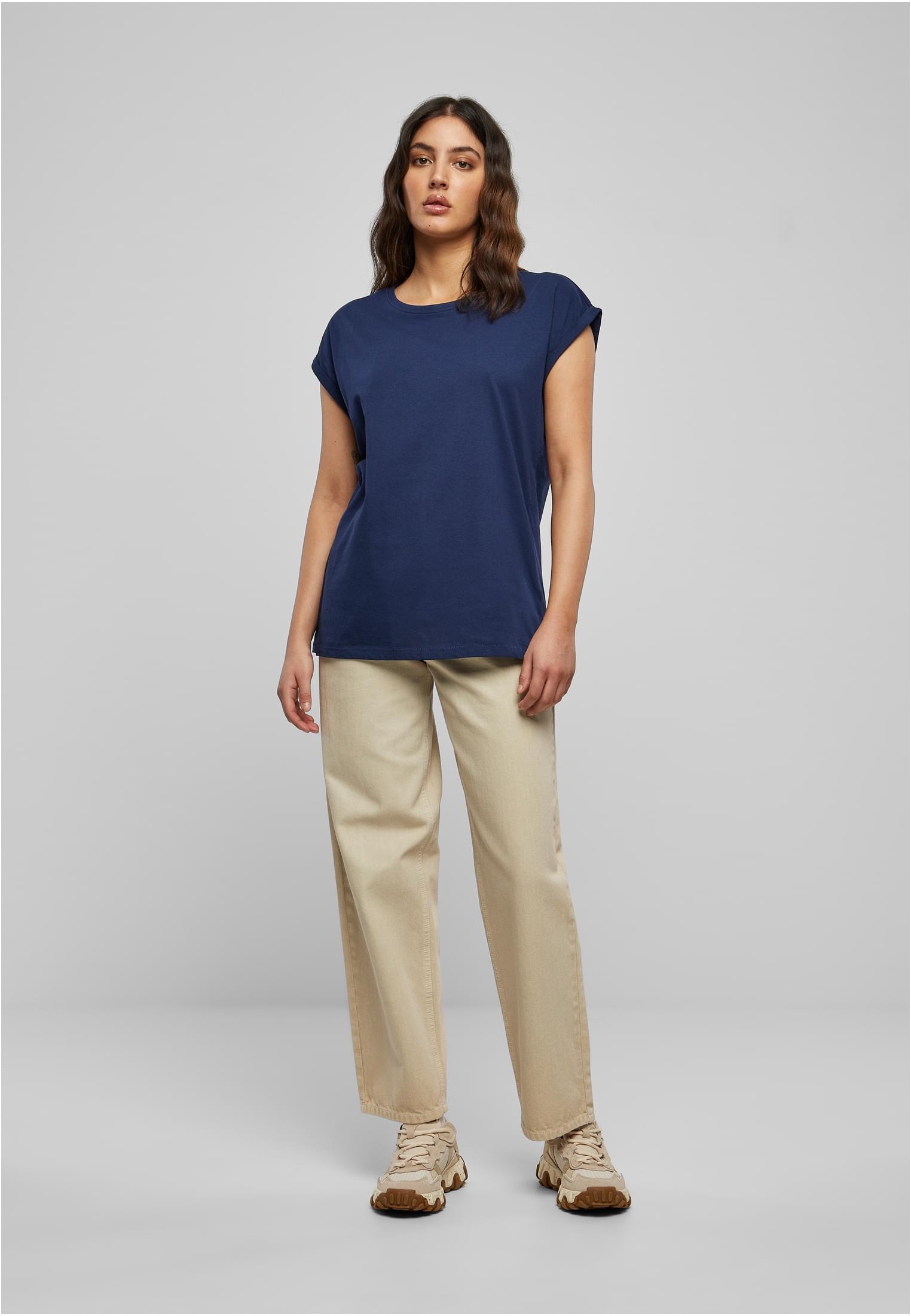 Helkroppsbild av en kvinna som bär en mörkblå Ladies Extended Shoulder Tee med beiga byxor och sneakers.