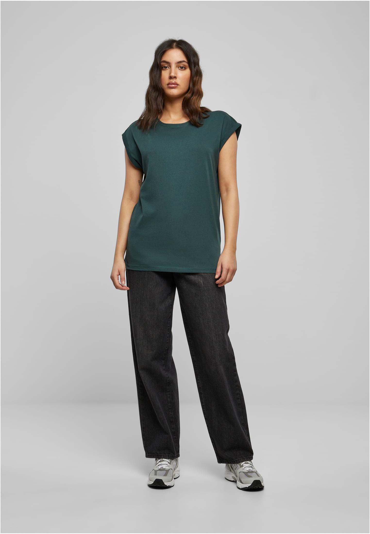 Modell som bär Ladies Extended Shoulder Tee i en mörkgrön nyans, stylad med svarta vida jeans och sneakers.