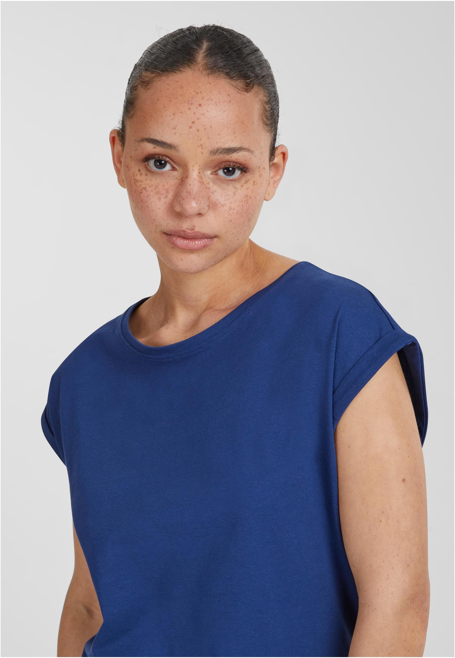 Närbild på en kvinna som bär en blå Ladies Extended Shoulder Tee från UC Ladies.
