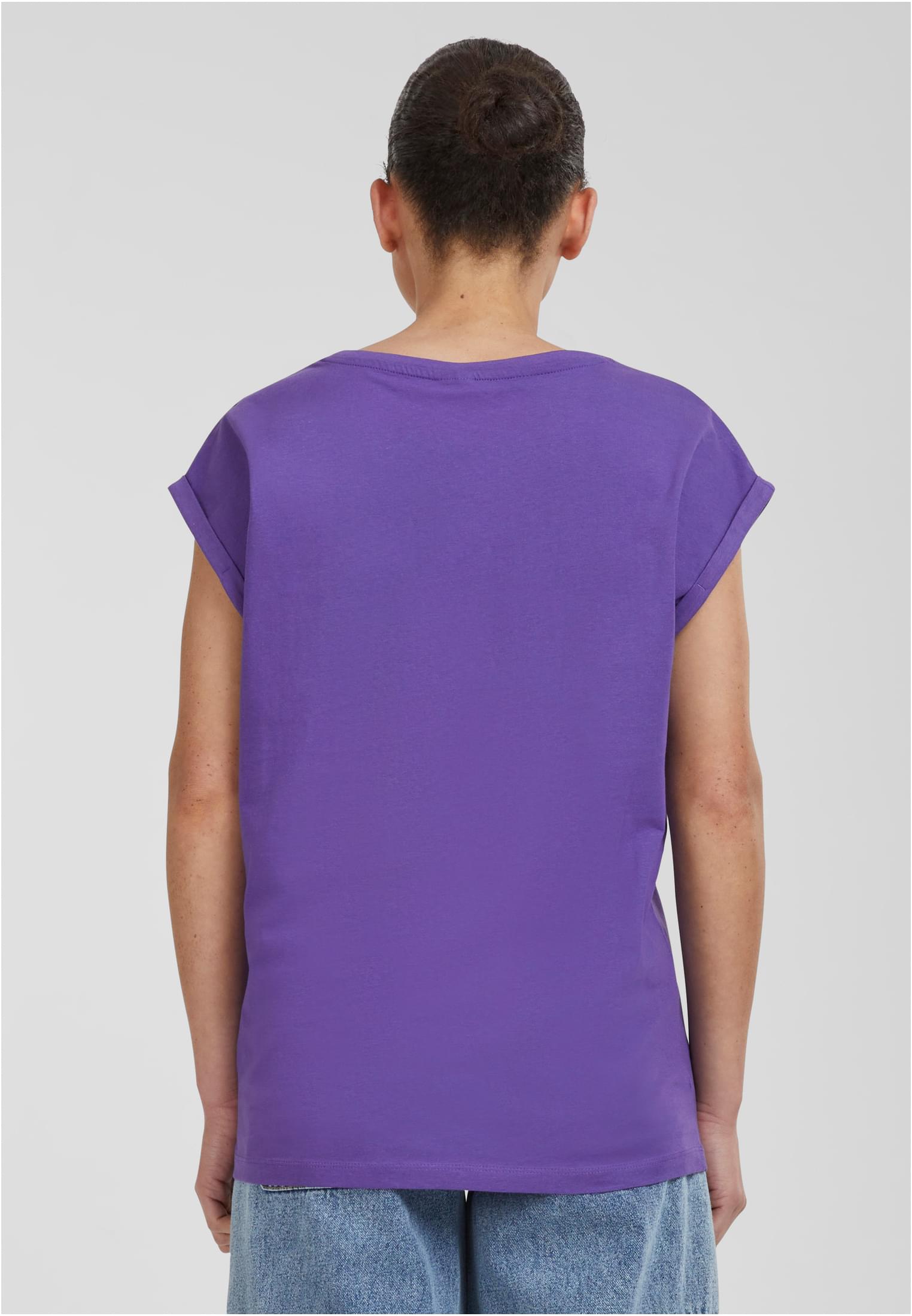 Kvinna sedd bakifrån i en lila t-shirt med nedhasade axlar och uppvikta ärmar.