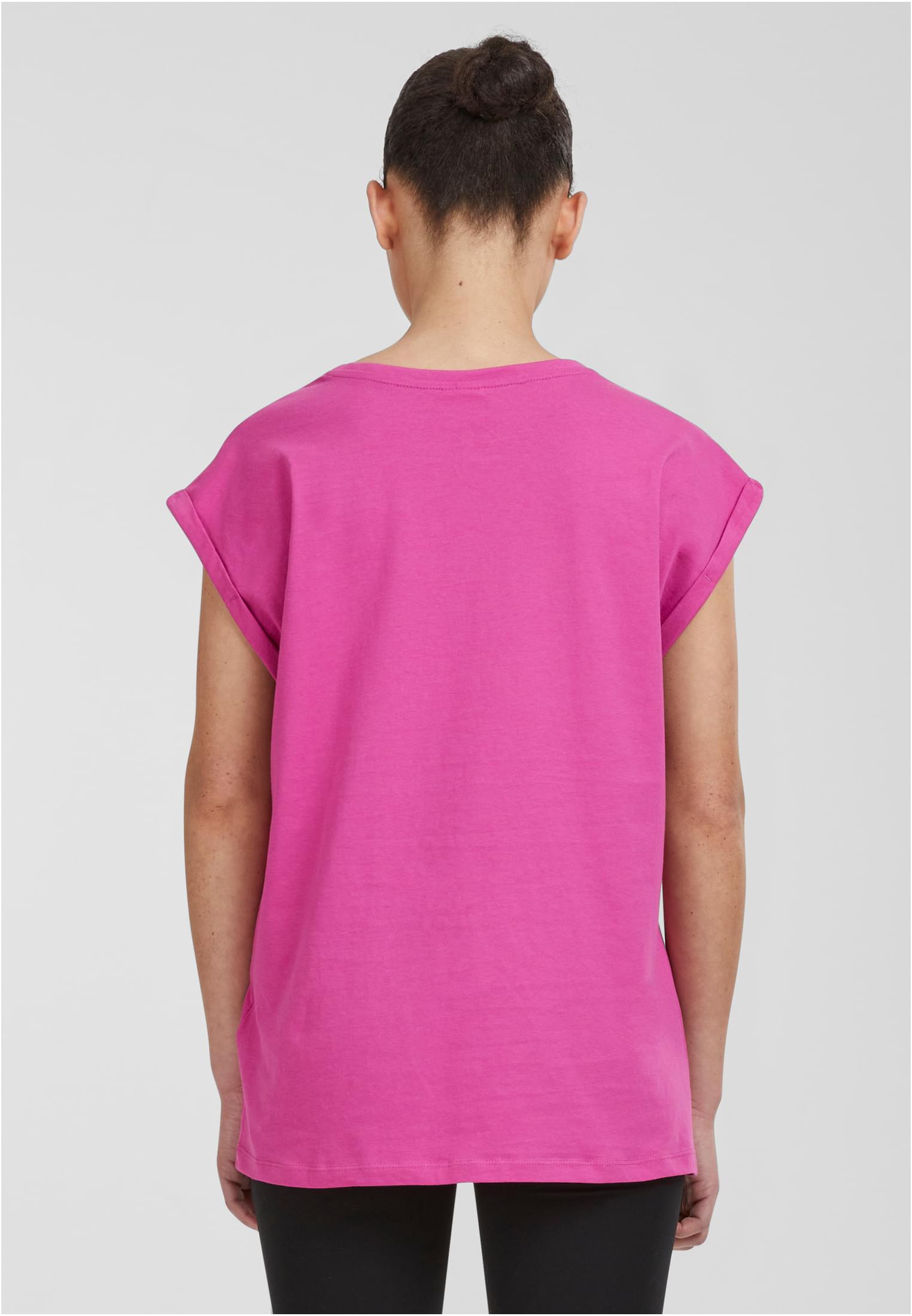 Baksidan av en modell som bär en rosa Ladies Extended Shoulder Tee med nedhasade axlar och uppvikta ärmar.