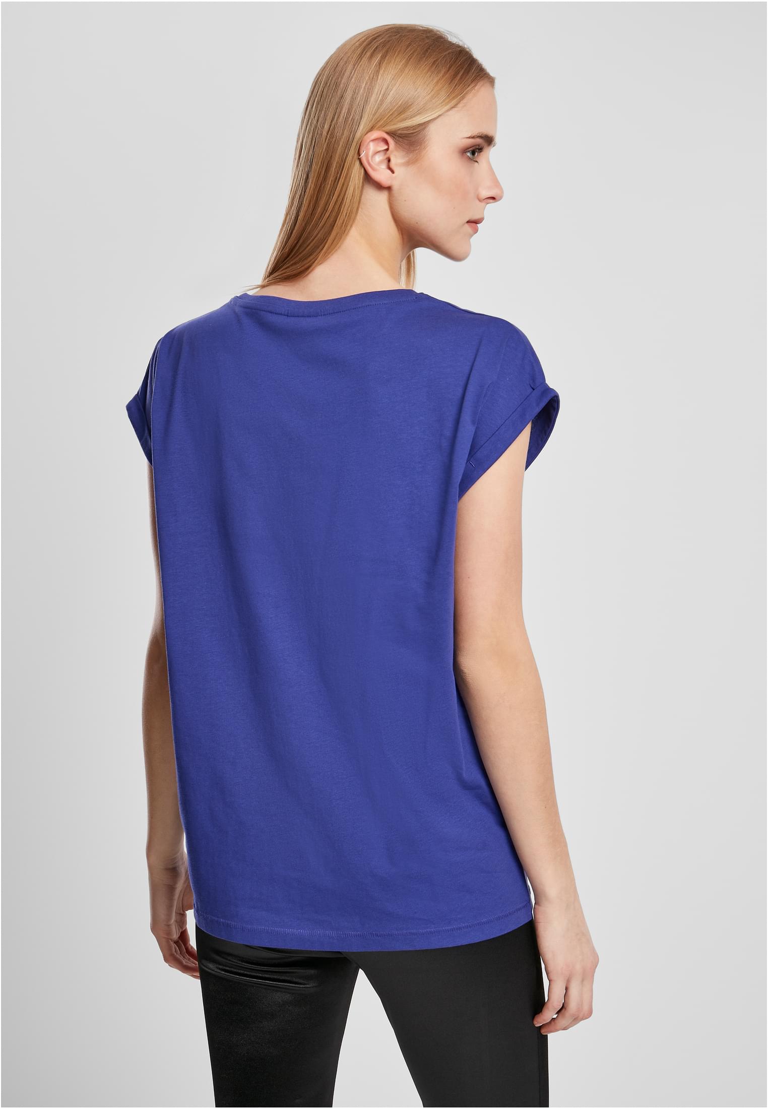 Baksidan av en kvinna som bär en blå Ladies Extended Shoulder Tee med nedhasade axlar och uppvikta ärmar.