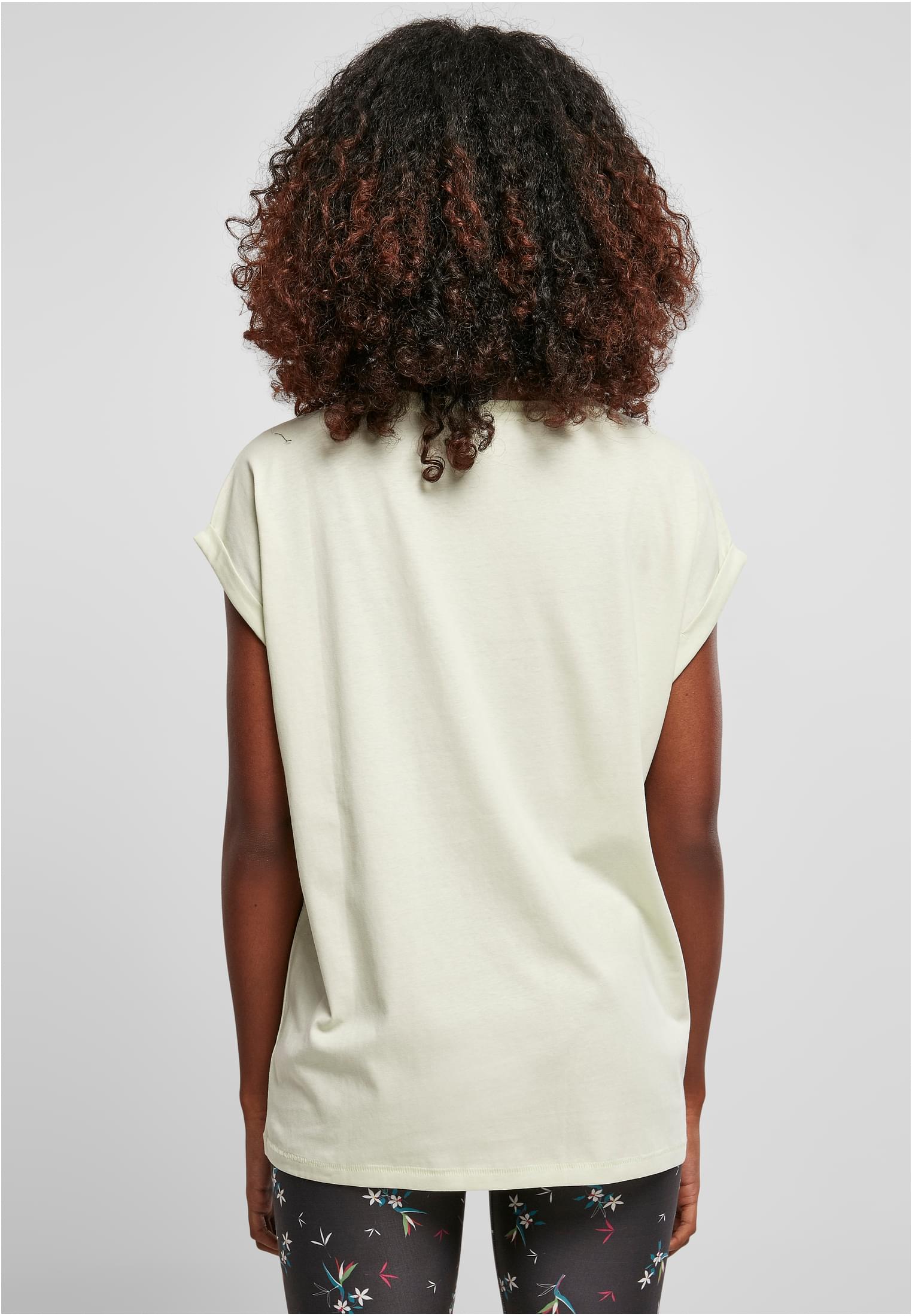 En kvinna fotograferad bakifrån, klädd i en ljusgrön Ladies Extended Shoulder Tee med uppvikta ärmar.