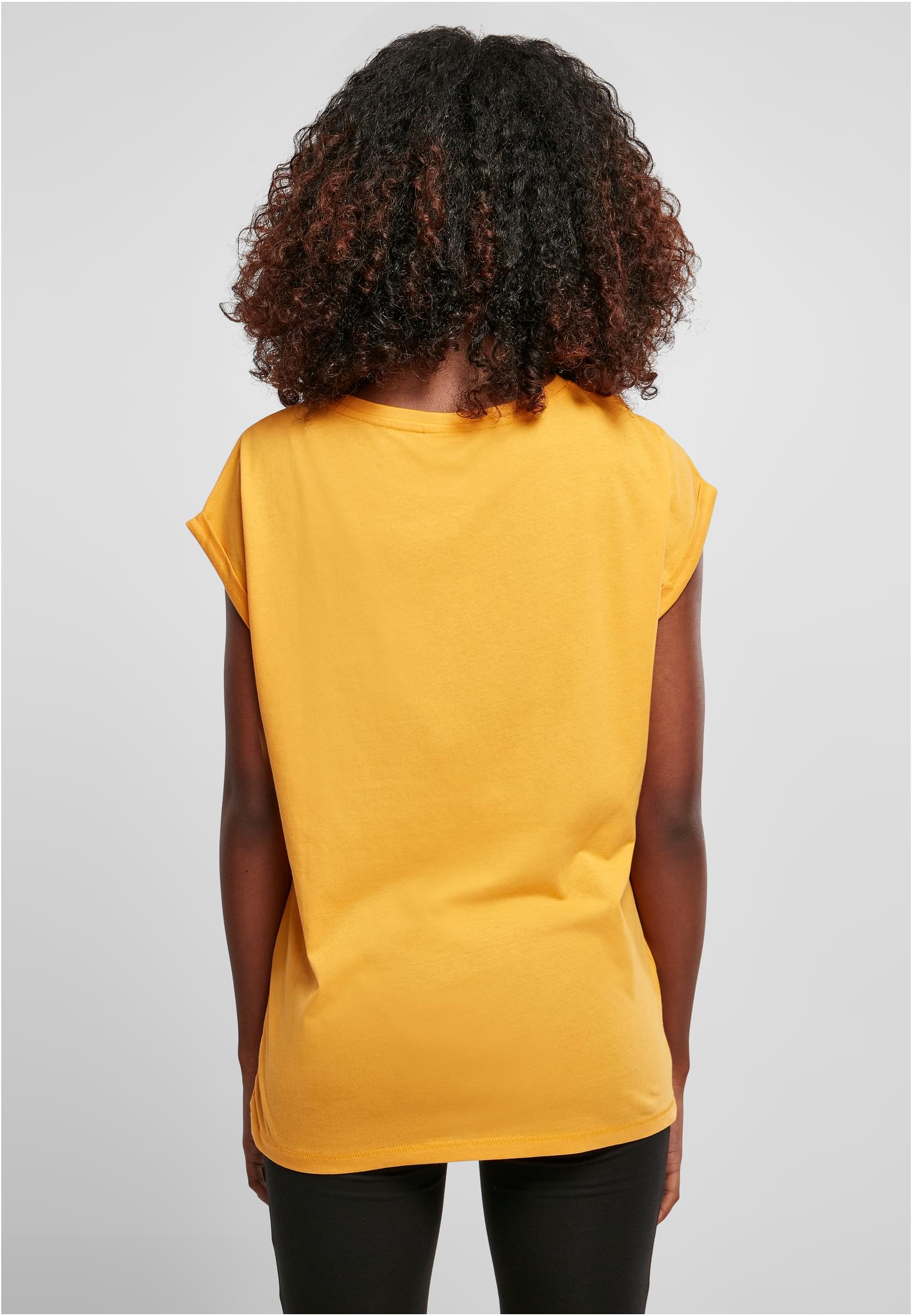 Baksidan av en kvinna som bär en gul t-shirt med nedhasade axlar och uppvikta ärmar.