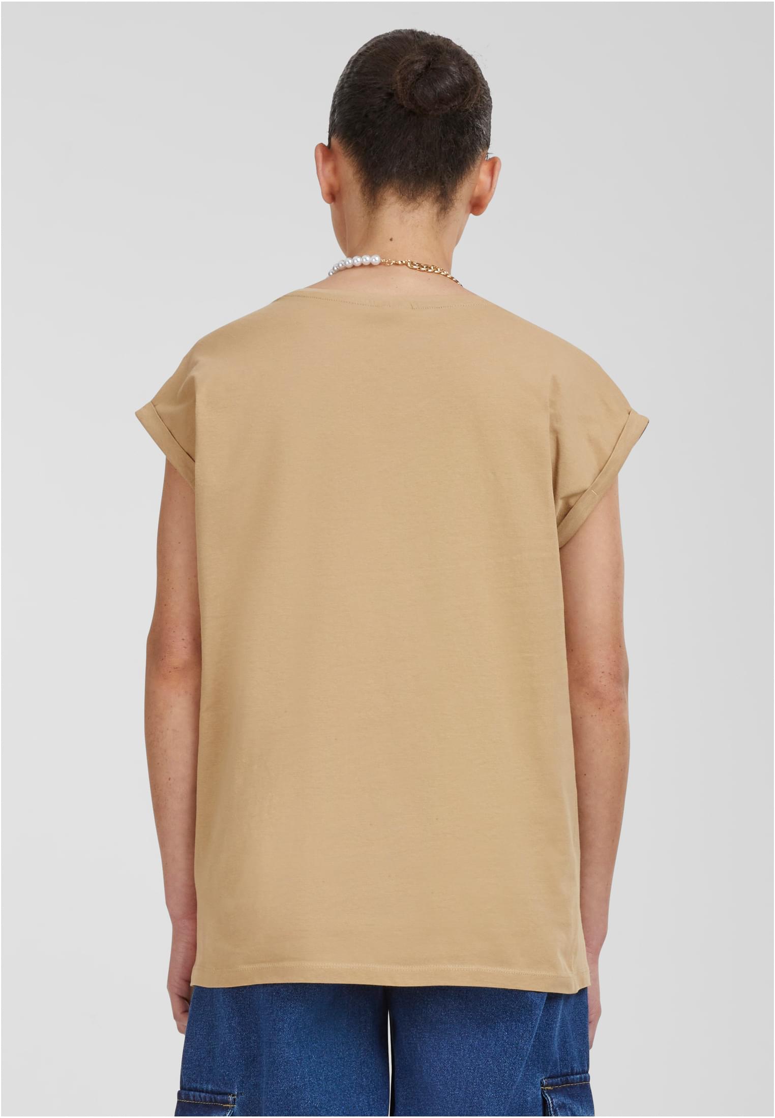 Baksidan av en kvinna som bär en beige Ladies Extended Shoulder Tee med uppvikta ärmar.