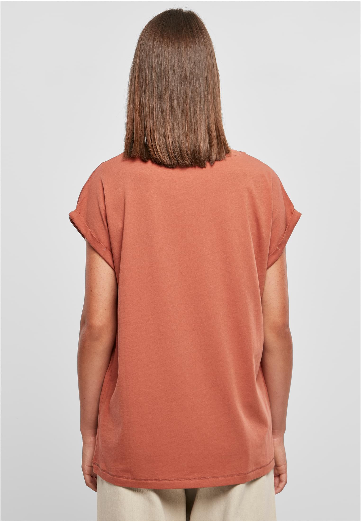 Baksidan av en modell som bär en ljusbrun Ladies Extended Shoulder Tee med uppvikta ärmar.