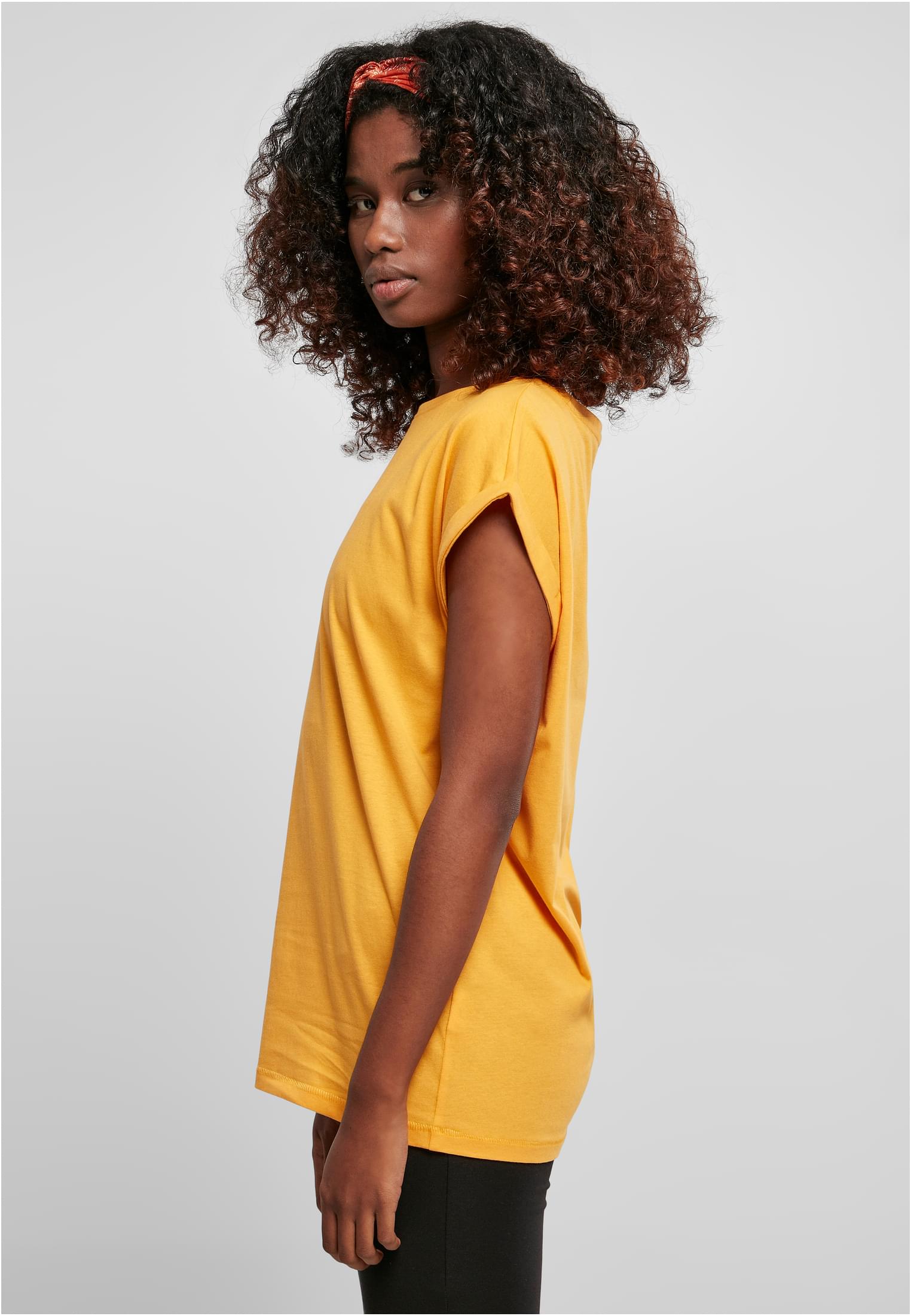 Sidovy av en kvinna med lockigt hår som bär en Ladies Extended Shoulder Tee.