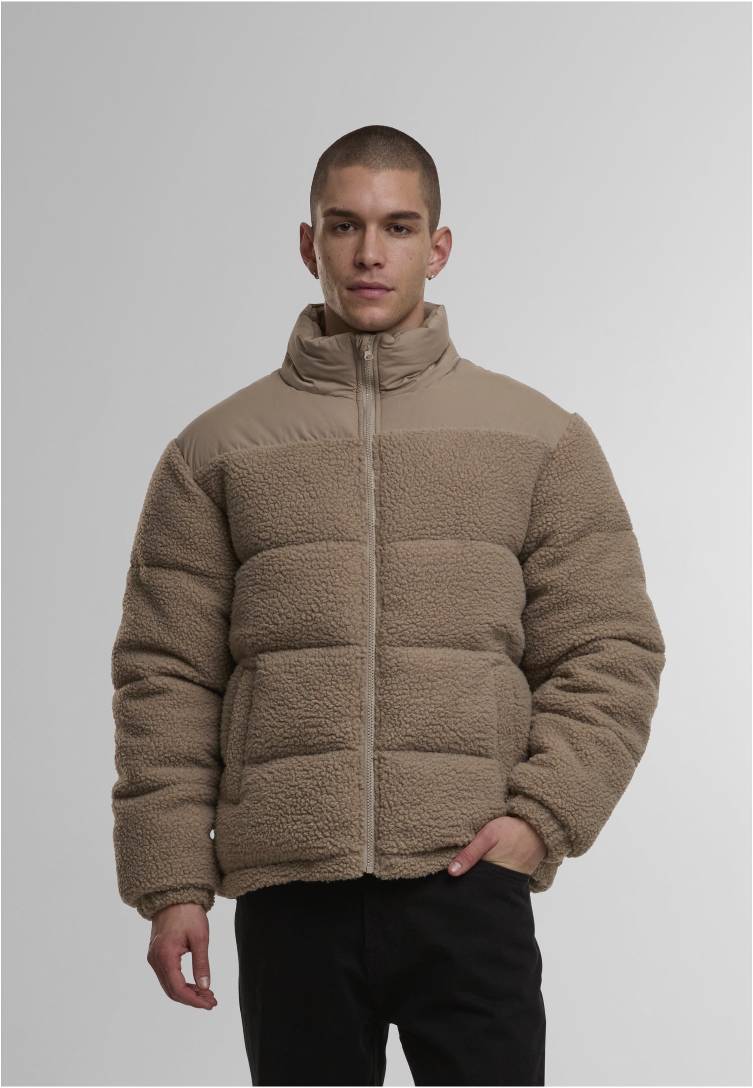 En manlig modell visar framsidan av den beiga UC Fabric Mix Teddy Puffer-jackan.